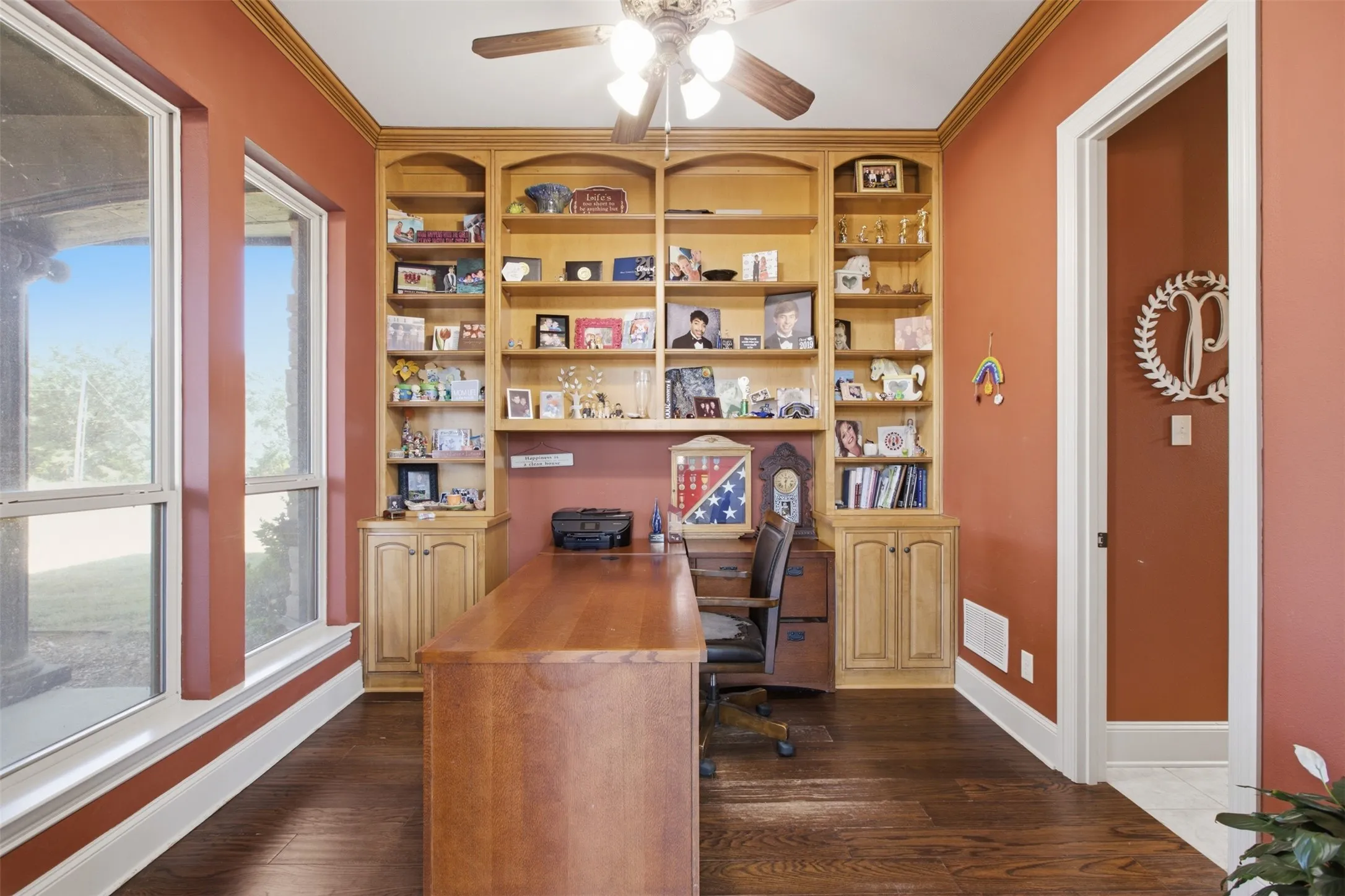 Built-in wood cabinetry with shelving, dark wood-finish flooring, white trim, and a ceiling fan with light fixture