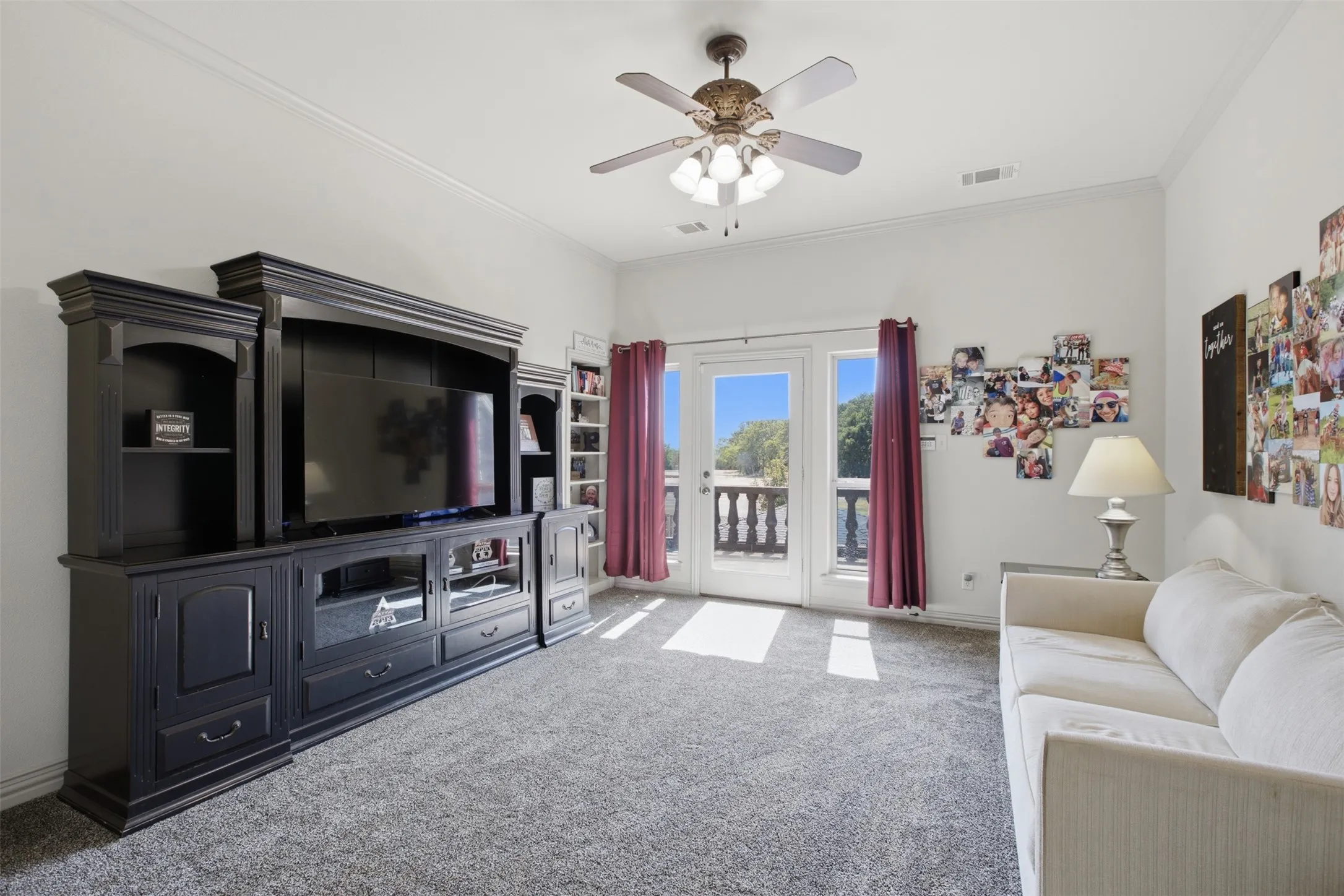 Built-in entertainment center, French doors to exterior, ceiling fan, and carpeted flooring