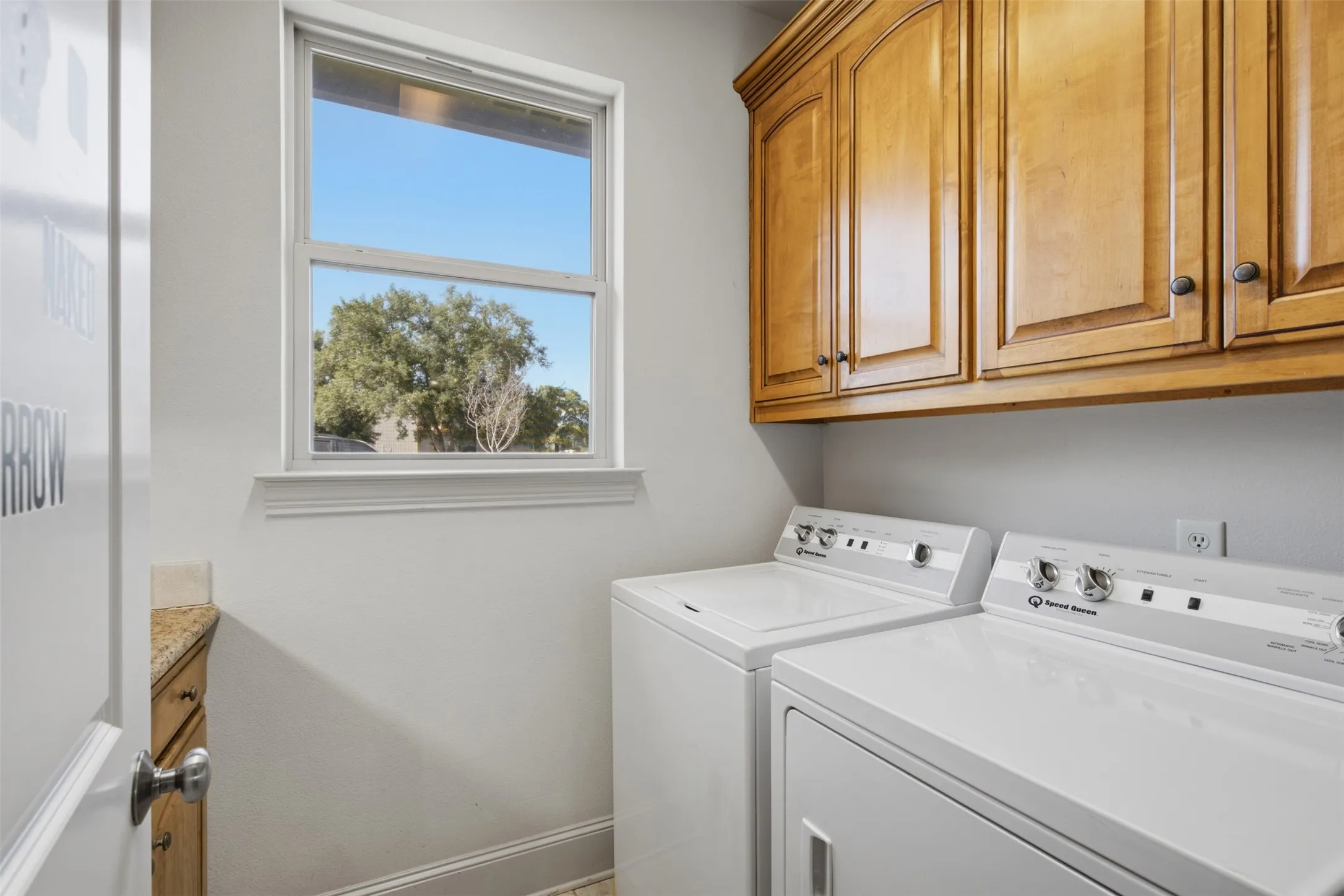 Laundry room featuring light wood cabinetry, a single window, and a built-in counter with a light-toned surface