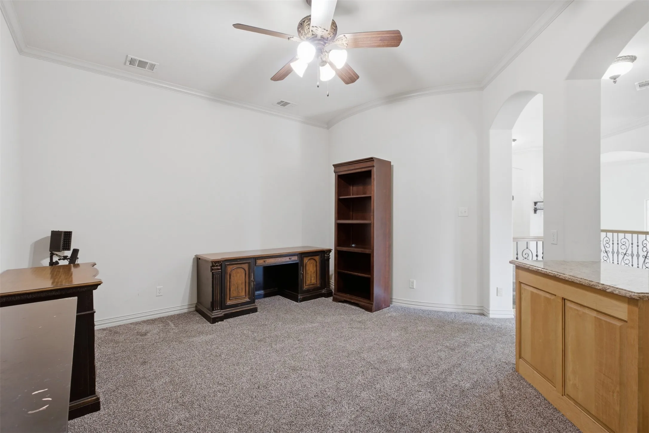 Archways frame an open-concept space with crown molding and a ceiling fan