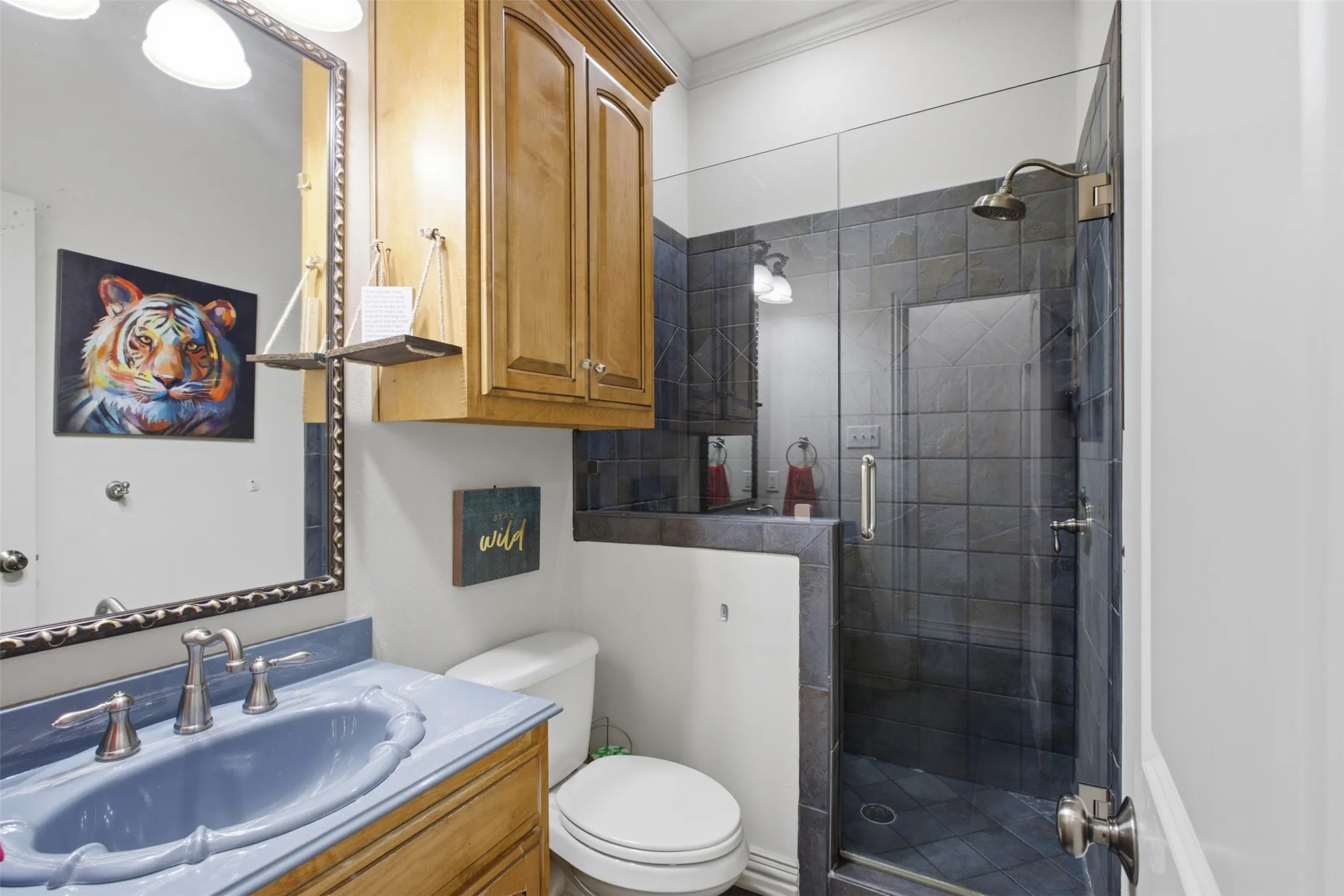 Glass-enclosed shower with dark tile surround, built-in storage cabinet, and brushed nickel fixtures