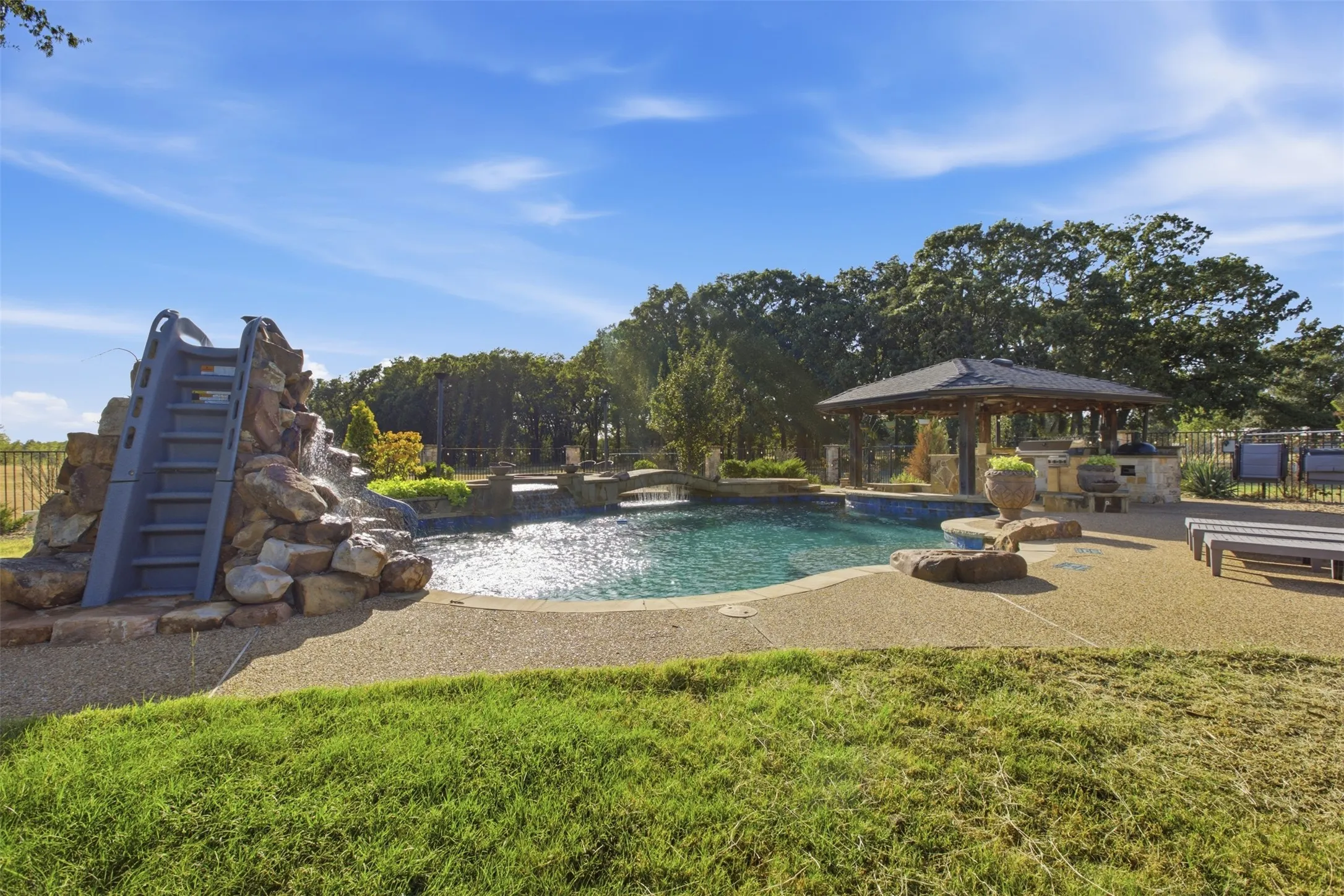 In-ground swimming pool featuring a rock waterfall and slide