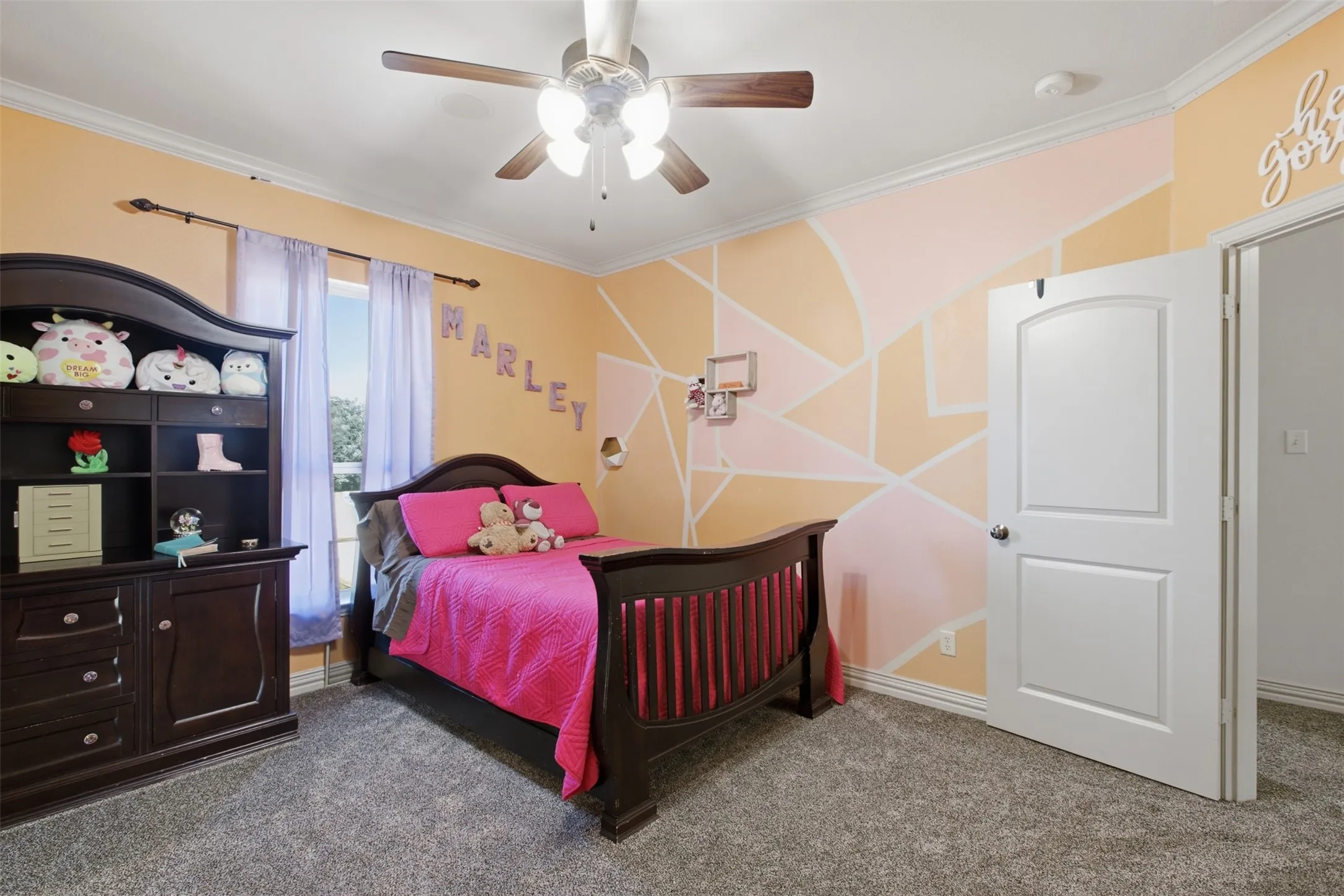Carpeted flooring, ceiling fan, white trim, arched panel interior door, and a built-in shelf unit