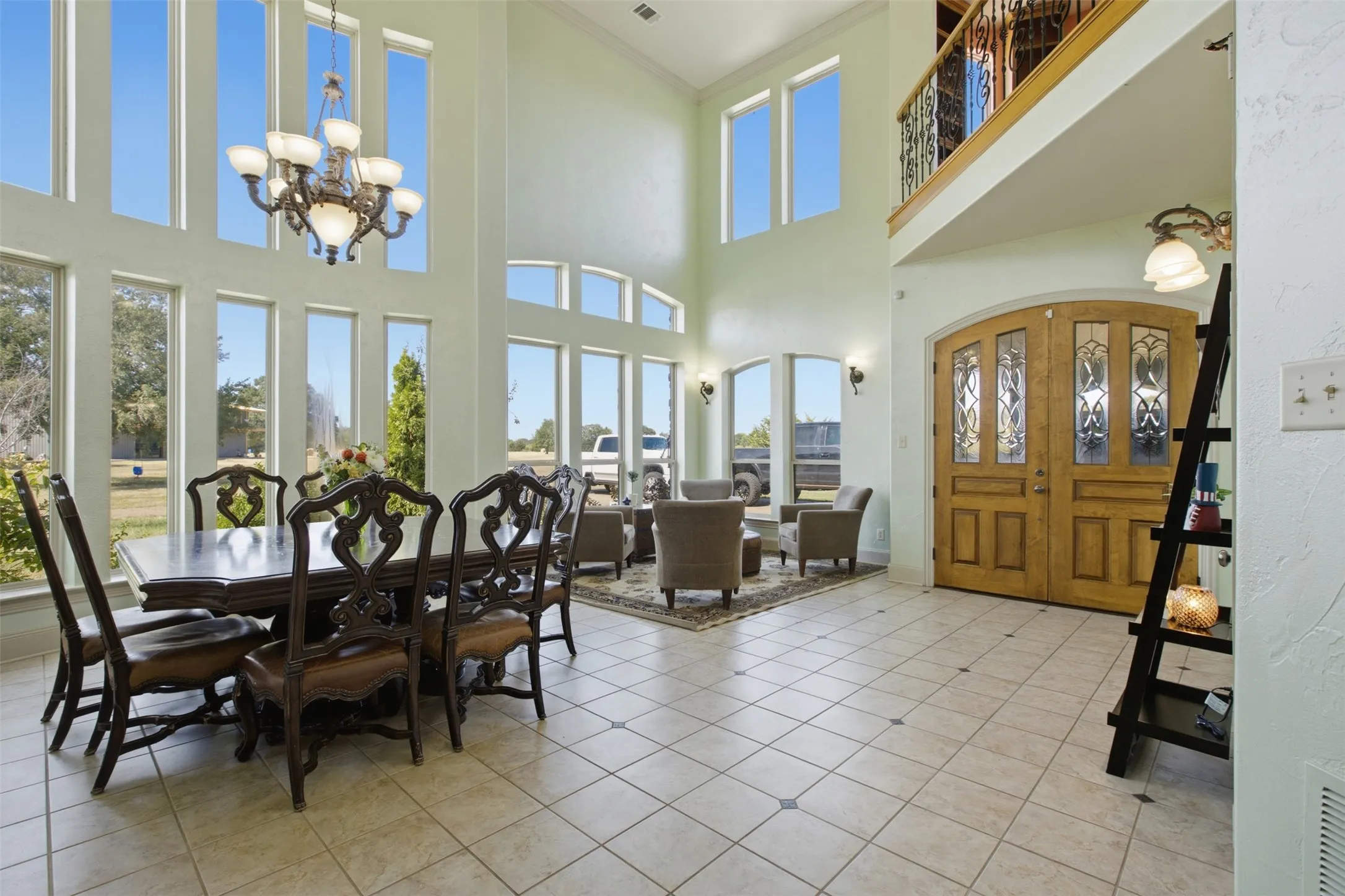 Two-story foyer with a double-door entry, a second-story balcony with an iron railing, and floor-to-ceiling windows