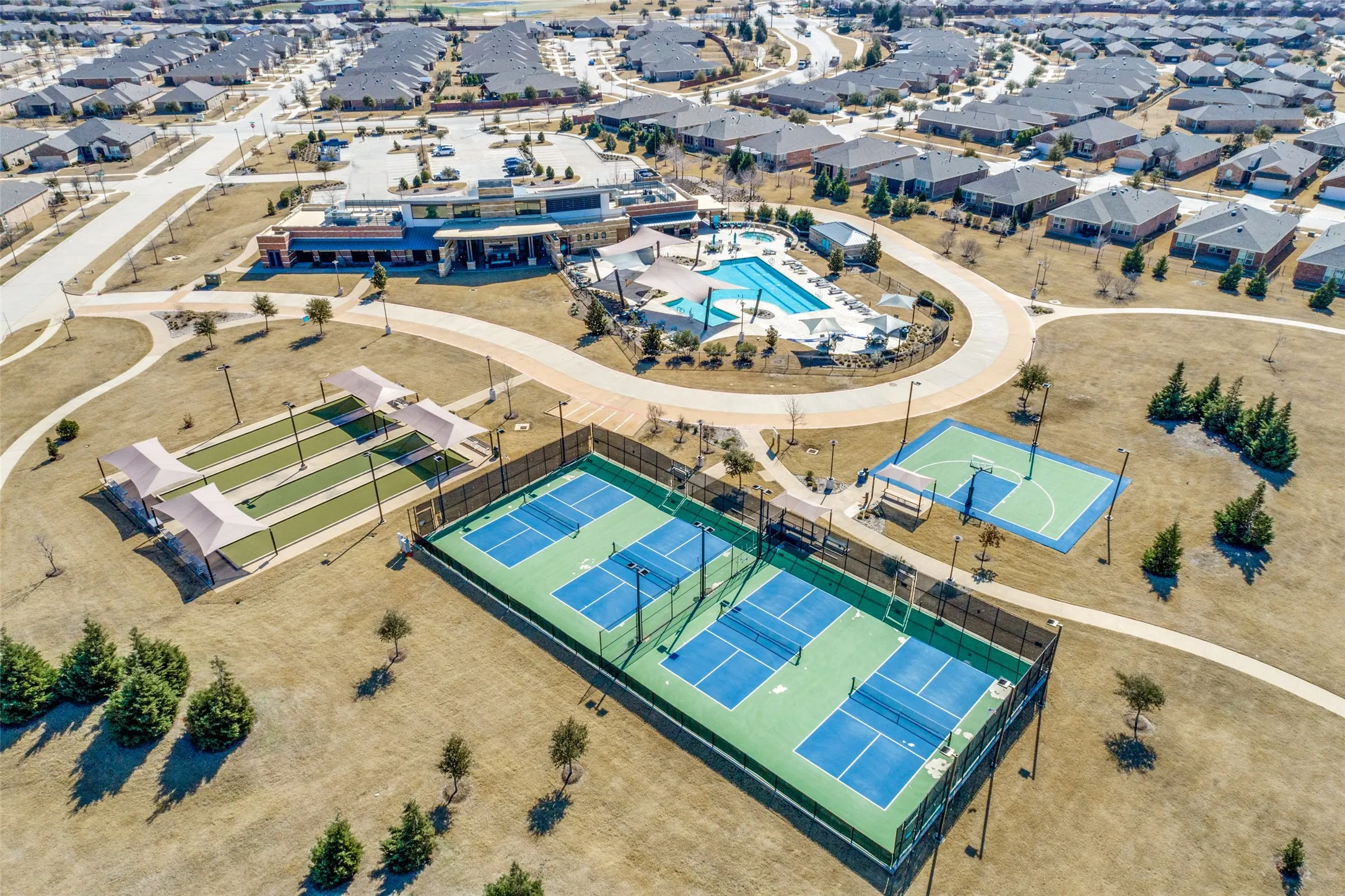 Community amenities featuring multiple pickleball courts, a basketball court, covered bocce ball courts, and a large swimming pool with surrounding lounge areas