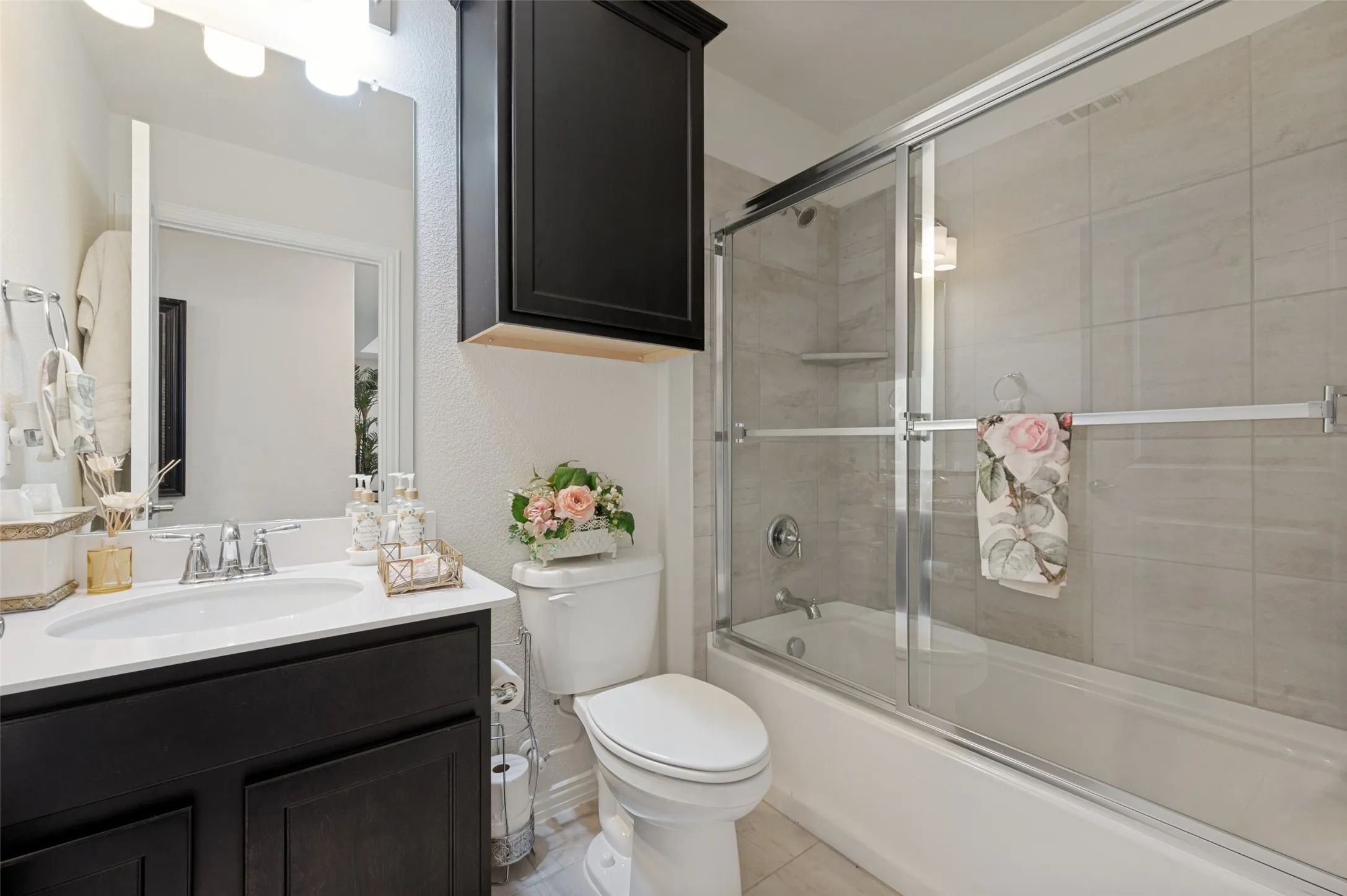 White vanity with a single basin, dark wood-finish cabinetry, and chrome fixtures