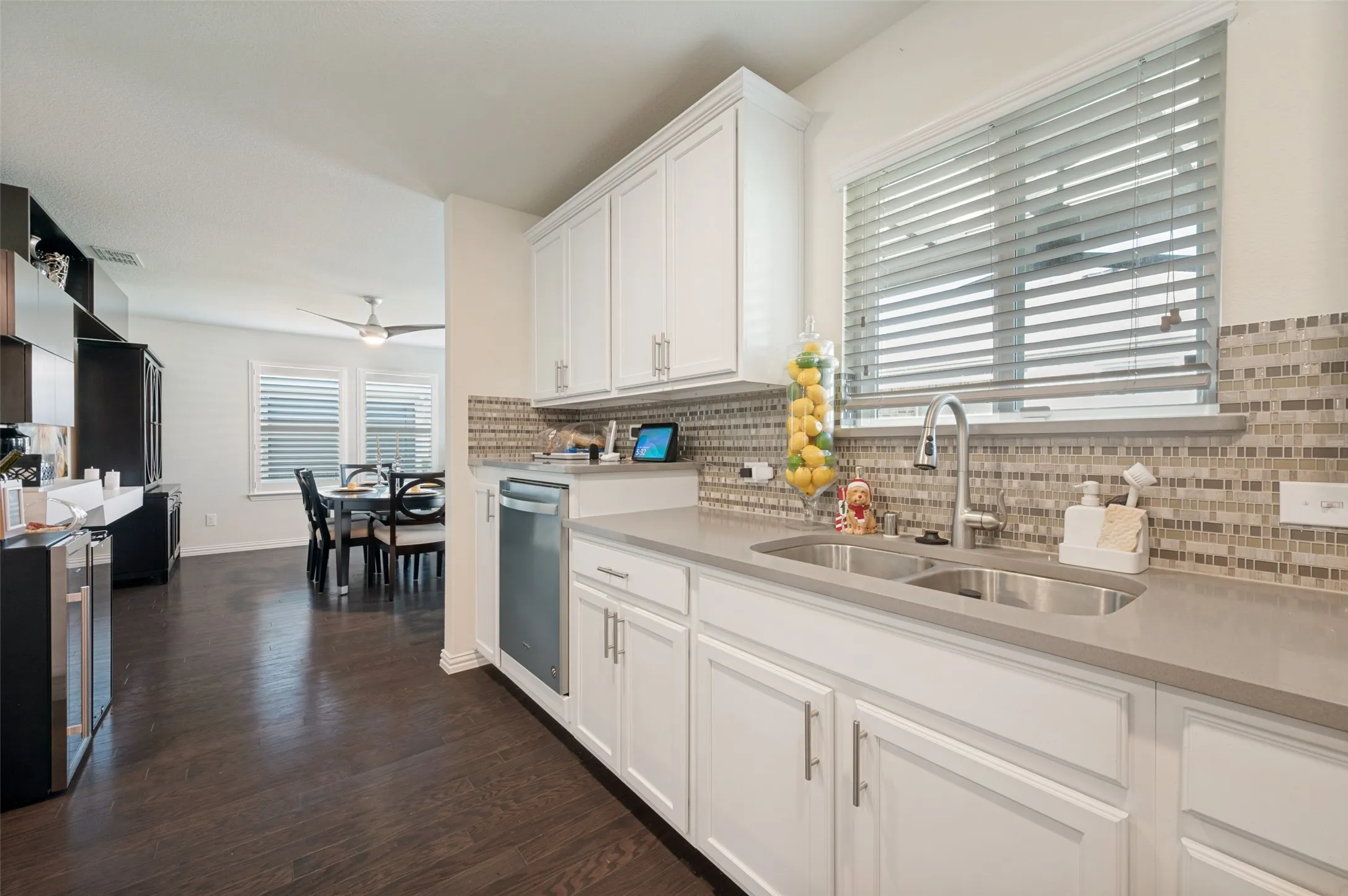 White shaker cabinetry, dual basin stainless steel sink, tile backsplash, wood-finish flooring, and recessed lighting