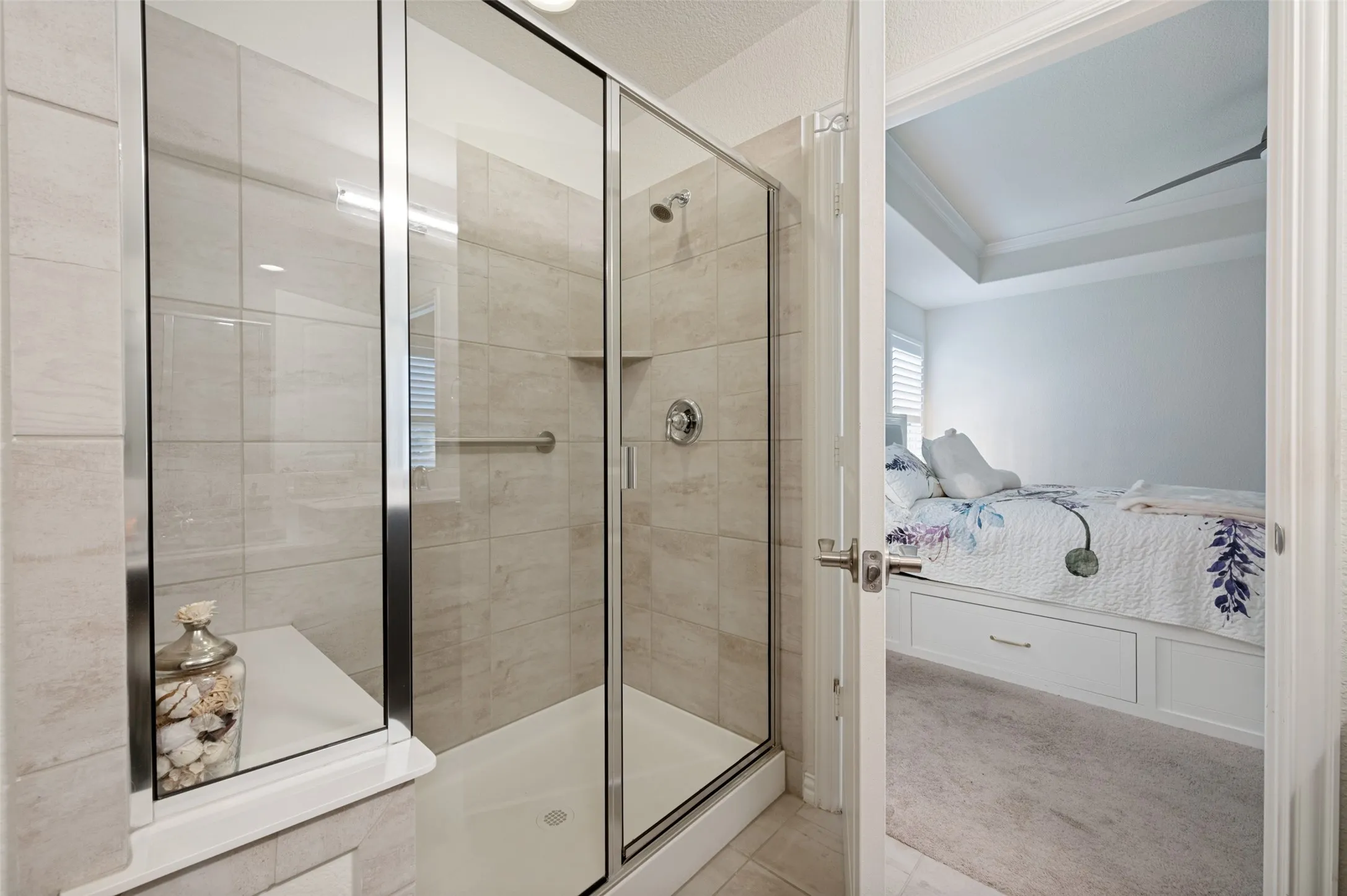 Glass-enclosed shower with a built-in bench, tiled walls, and a recessed shower niche