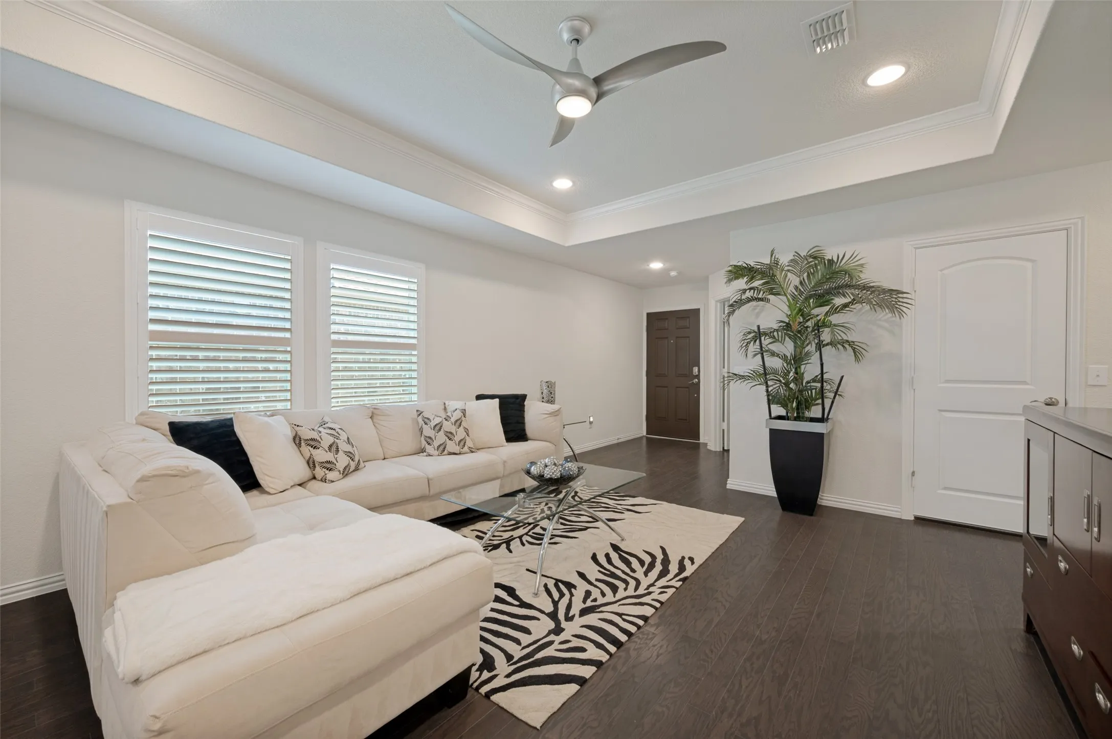 Recessed lighting, wood-finish flooring, tray ceiling with crown molding, and a contemporary ceiling fan