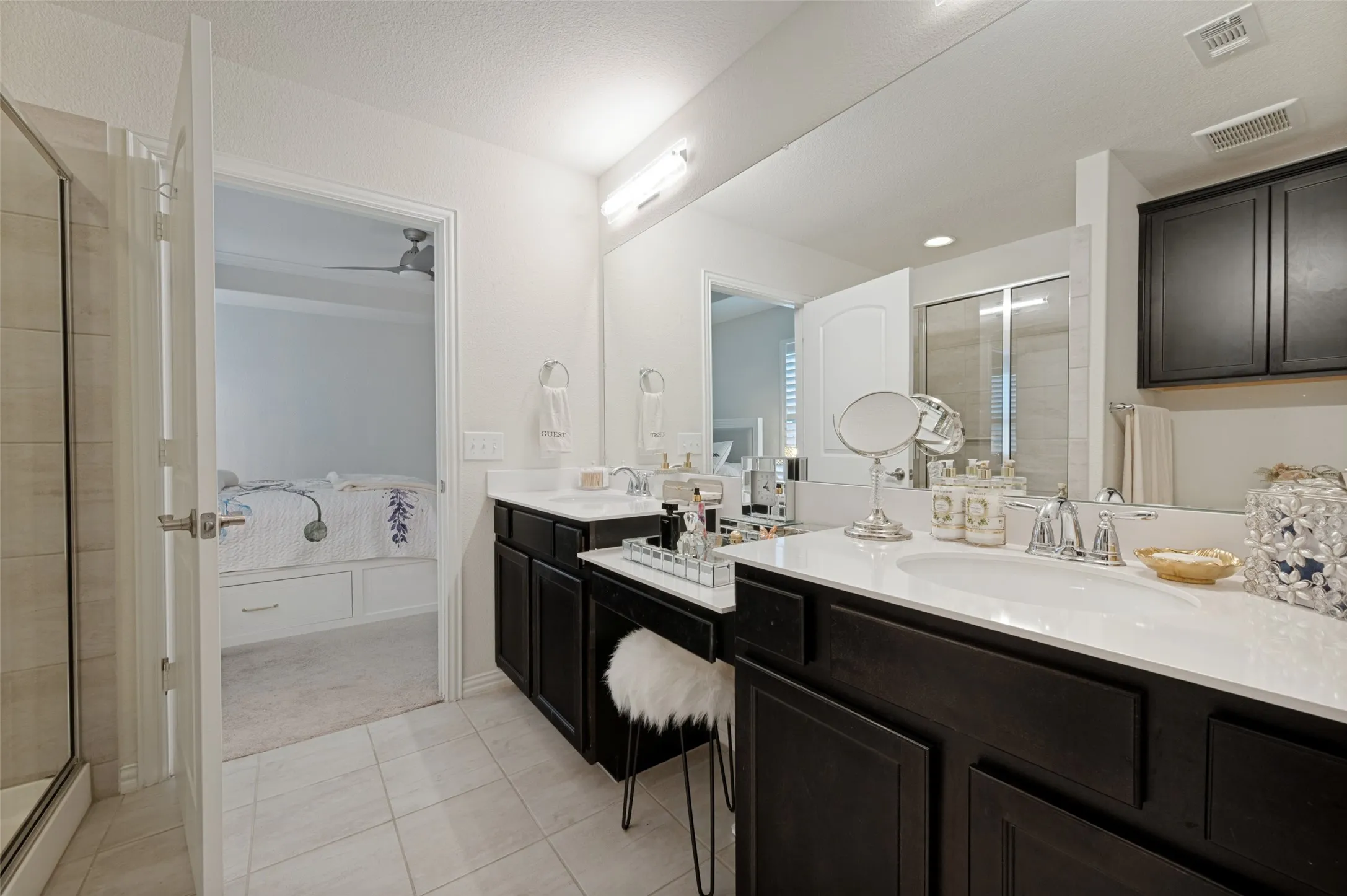 Bathroom featuring a dual vanity with white countertops, dark wood-finish cabinetry, and a walk-in shower with glass enclosure