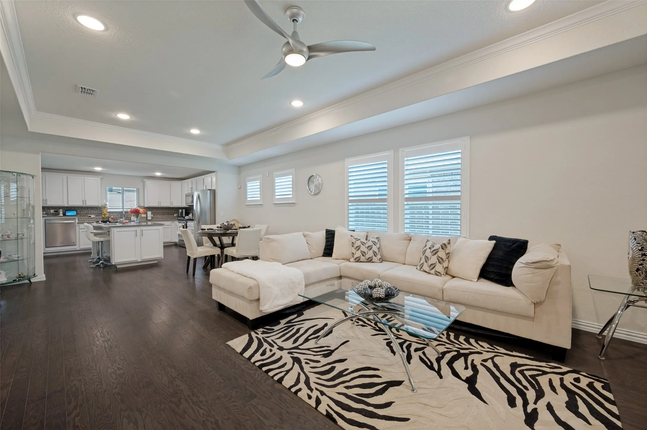 Open-concept living area featuring wood-finish flooring, recessed lighting, a modern ceiling fan, and white window​​‌​​​​‌​​‌‌​‌‌​​​‌‌​‌​‌​‌​​​‌​​ shutters