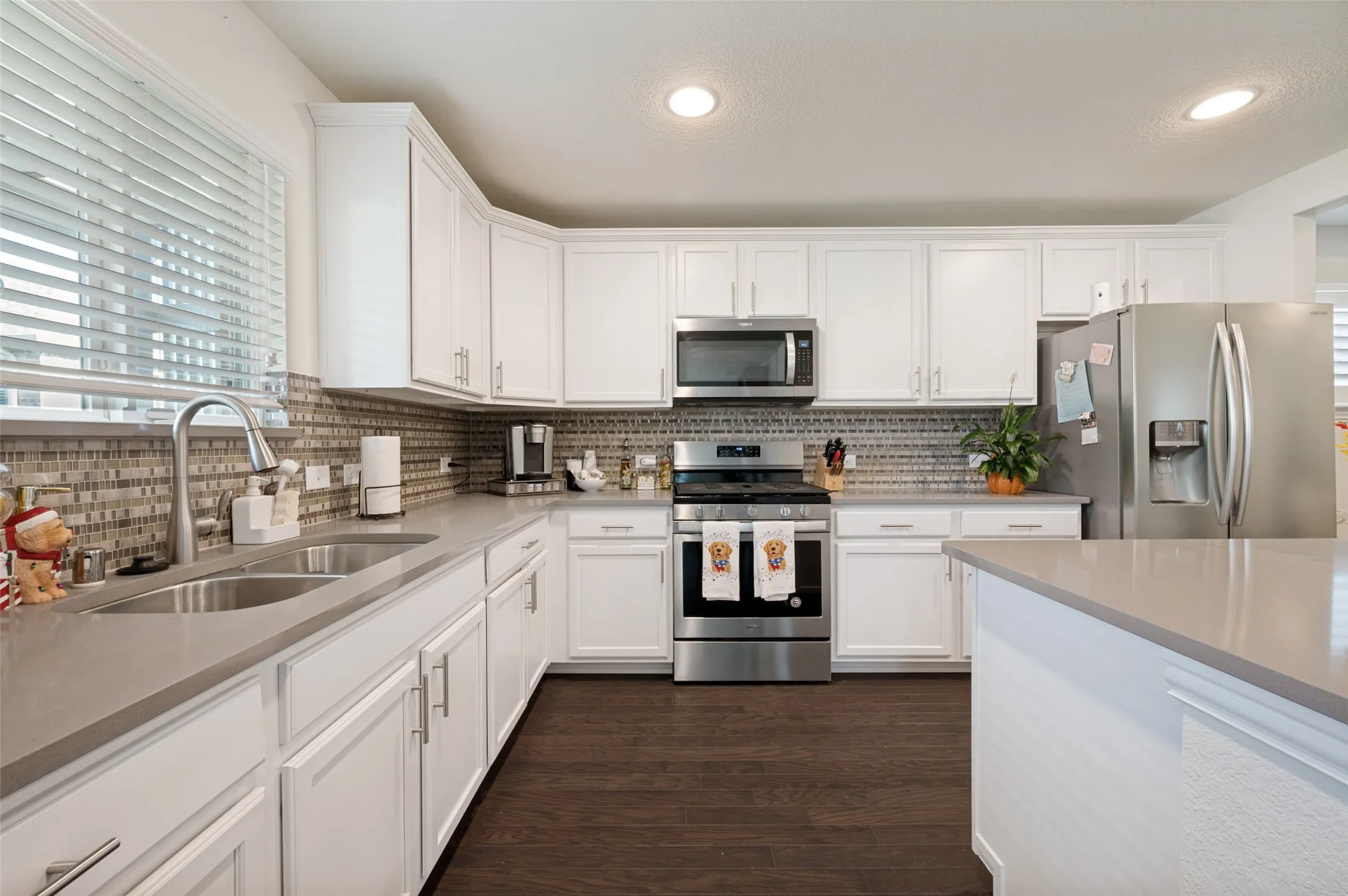 Modern kitchen featuring white cabinetry, stainless steel appliances, a mosaic tile backsplash, and wood-finish flooring