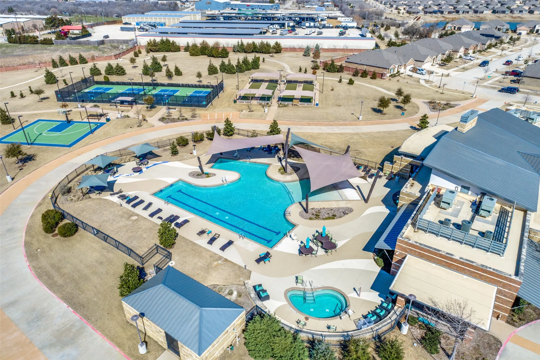Resort-style pool with integrated spa, multiple shade structures, and adjacent hardscape patio