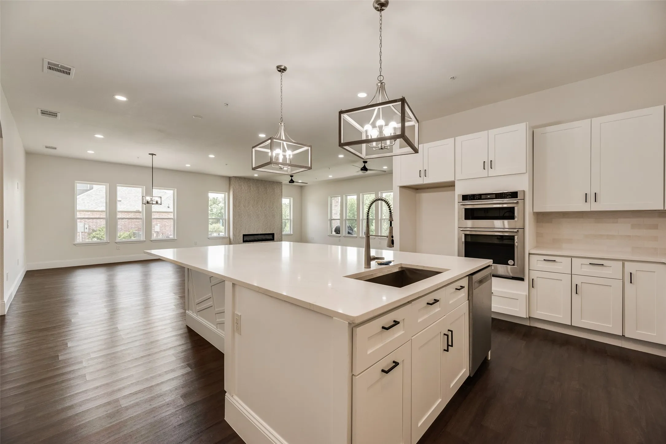 Spacious kitchen featuring an expansive island with a built-in sink, stainless steel appliances, white cabinetry, and recessed lighting