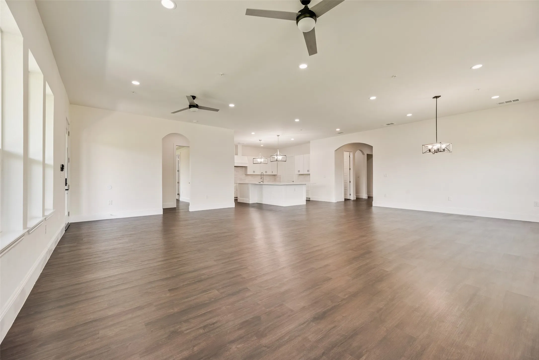 Spacious living area featuring wood-finish flooring, recessed lighting, and ceiling fans