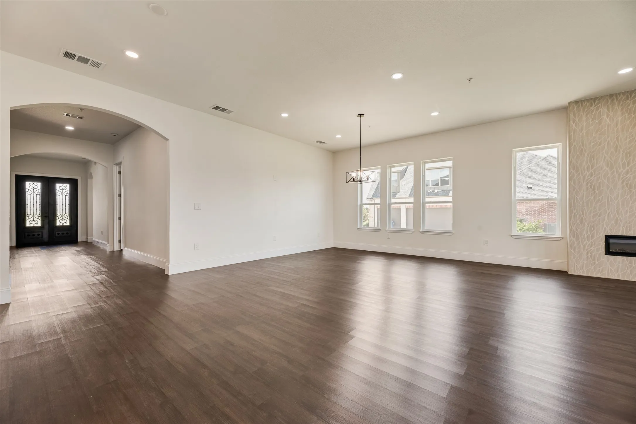 Spacious living area featuring wood-finish flooring, recessed lighting, and multiple windows
