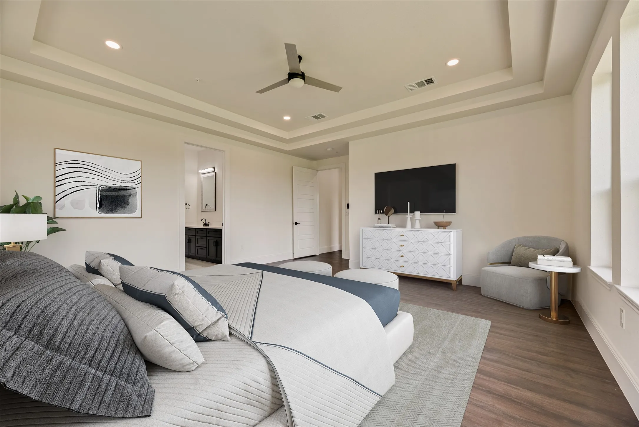 Tray ceiling with recessed lighting and a ceiling fan, wood-finish flooring, and multiple windows with white trim