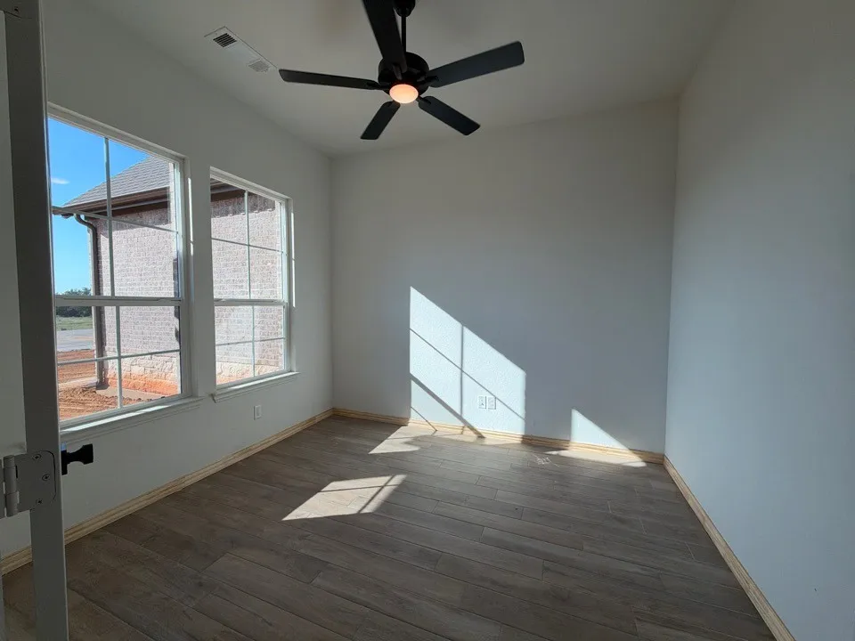 Wood-finish tile flooring, dual double-hung windows, and a black ceiling fan with integrated lighting