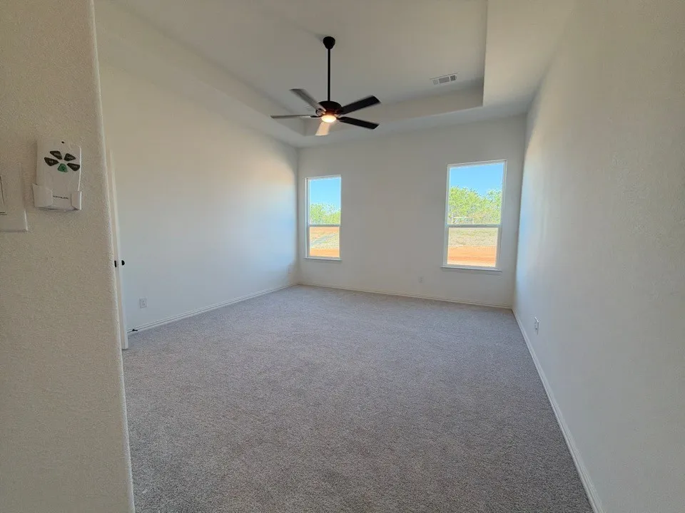 Recessed ceiling with an integrated ceiling fan, two windows, and gray carpet