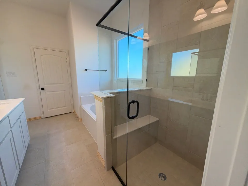 Walk-in shower with clear glass enclosure, integrated bench, and tiled walls