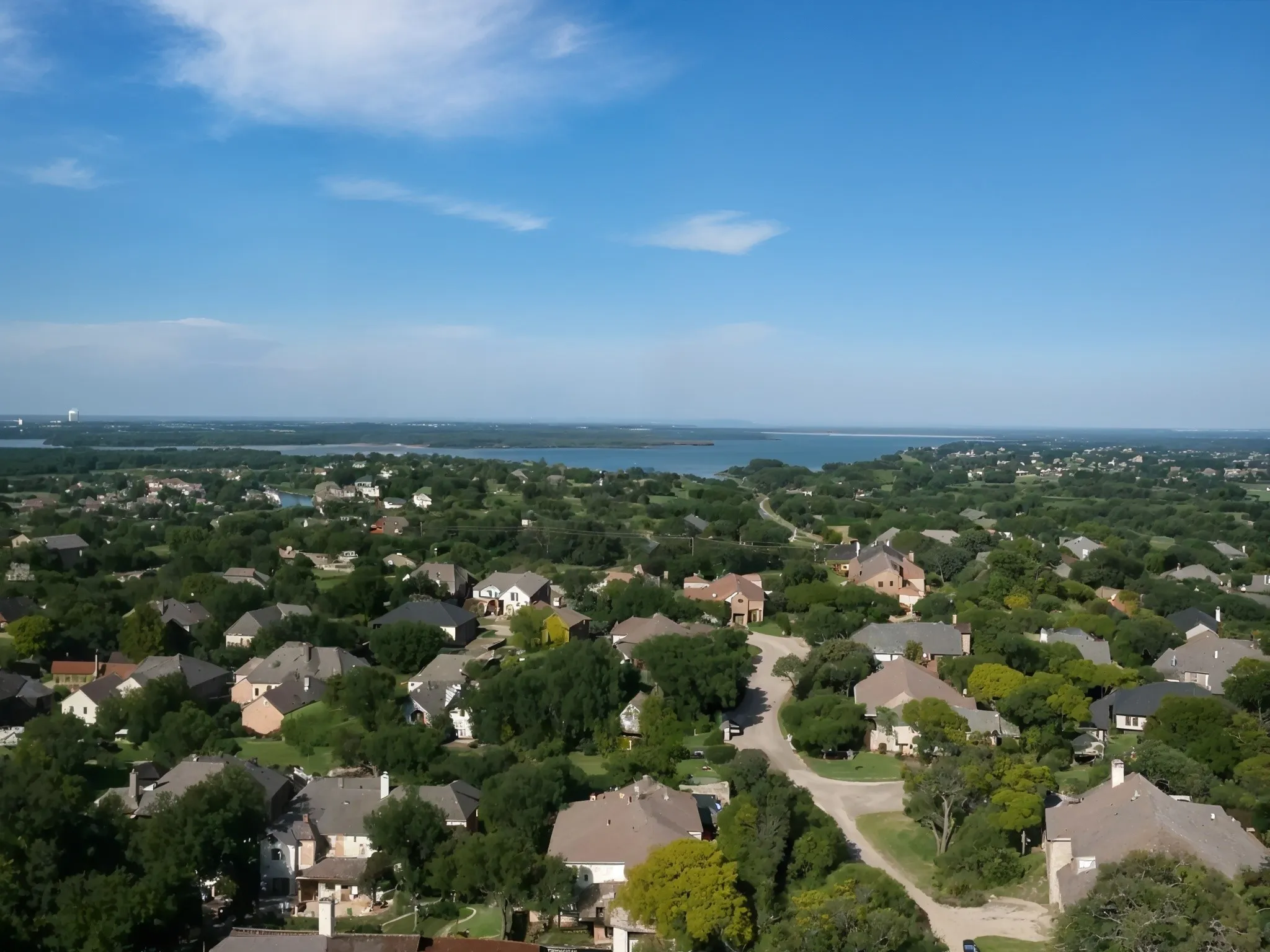 Expansive residential neighborhood with mature trees, established homes, and distant water body