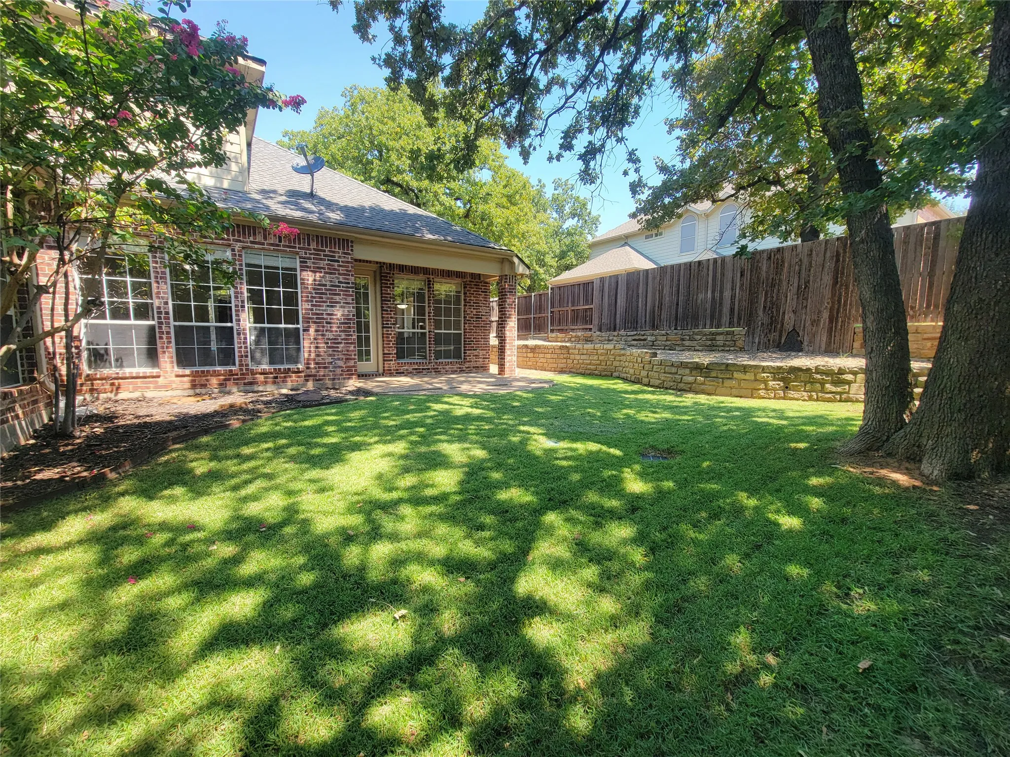 Brick exterior with a covered patio and multiple large windows