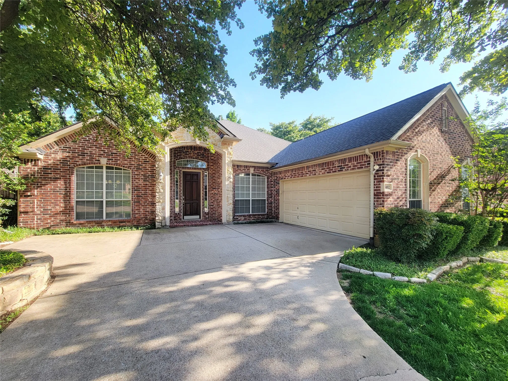 Brick exterior with stone accents, arched entry, and an attached two-car garage