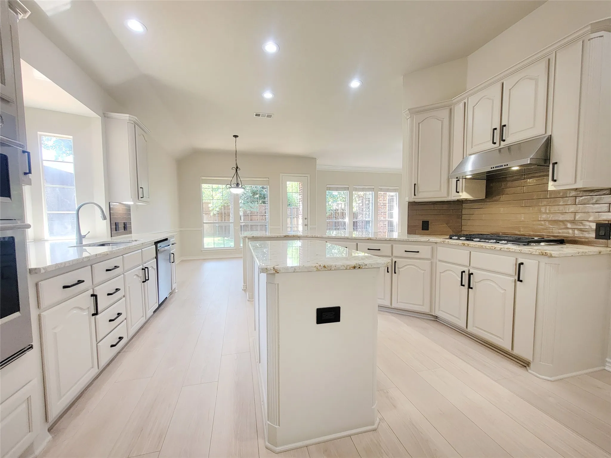 Kitchen featuring white cabinetry, light-toned wood-finish flooring, recessed lighting, and a kitchen island with stone countertops