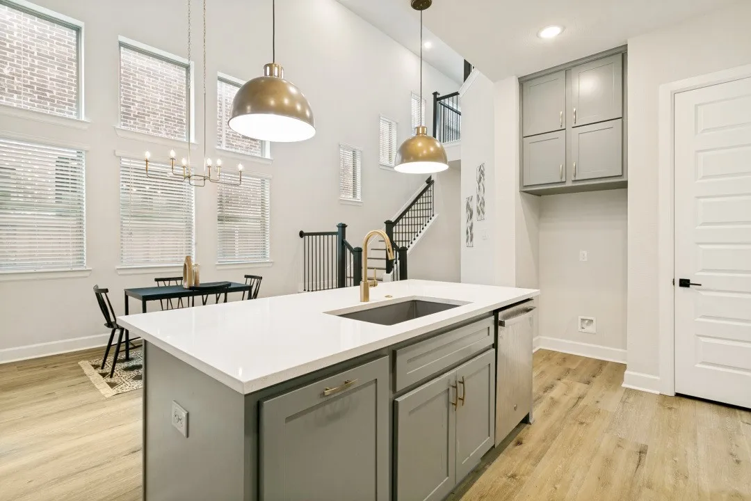 Kitchen island with white countertop and integrated sink, featuring two pendant lights