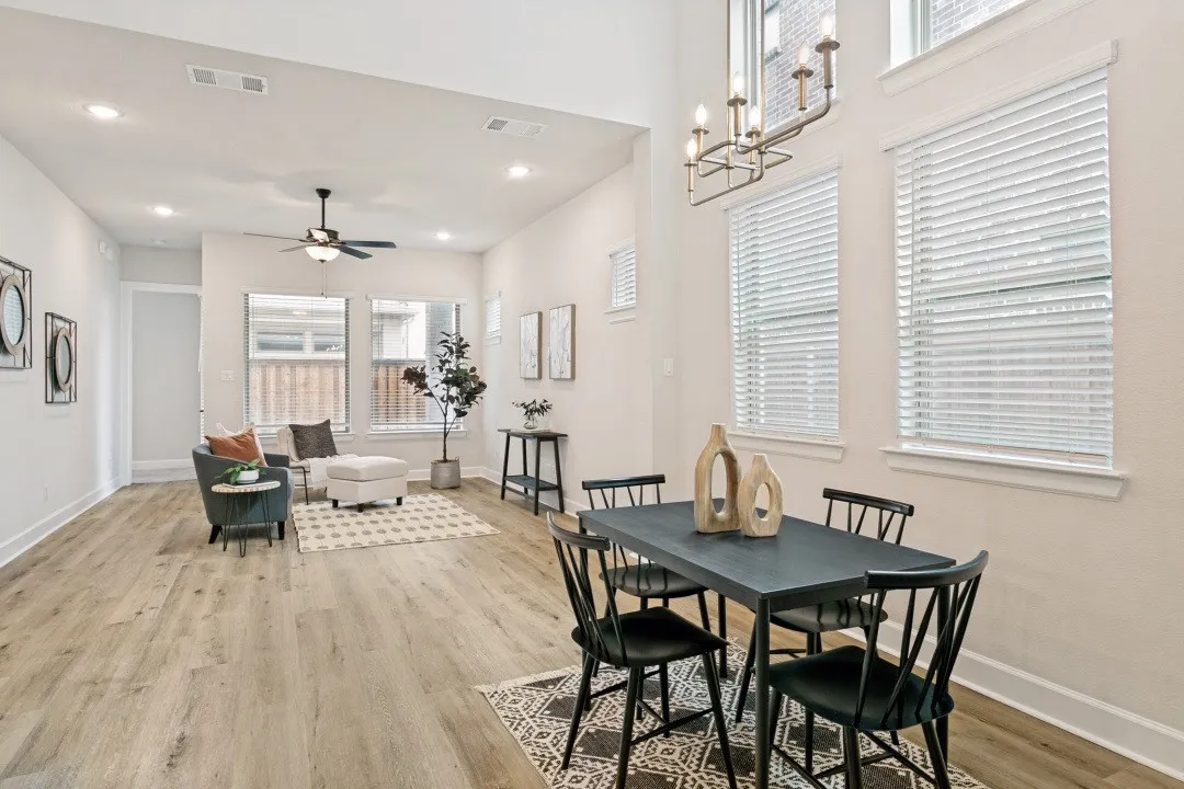 Open-concept living and dining areas featuring wood-finish flooring, recessed lighting, high ceilings, and multiple windows with blinds