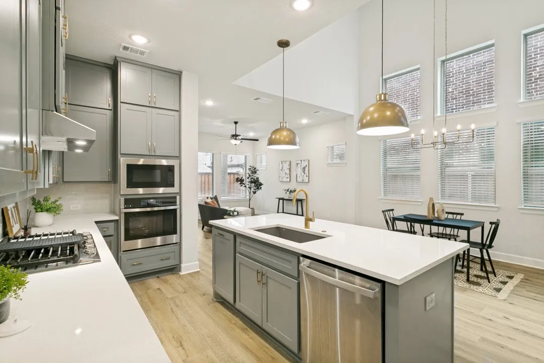 Contemporary kitchen featuring light gray cabinetry, stainless steel appliances, a center island with sink and integrated dishwasher, and wood-finish flooring