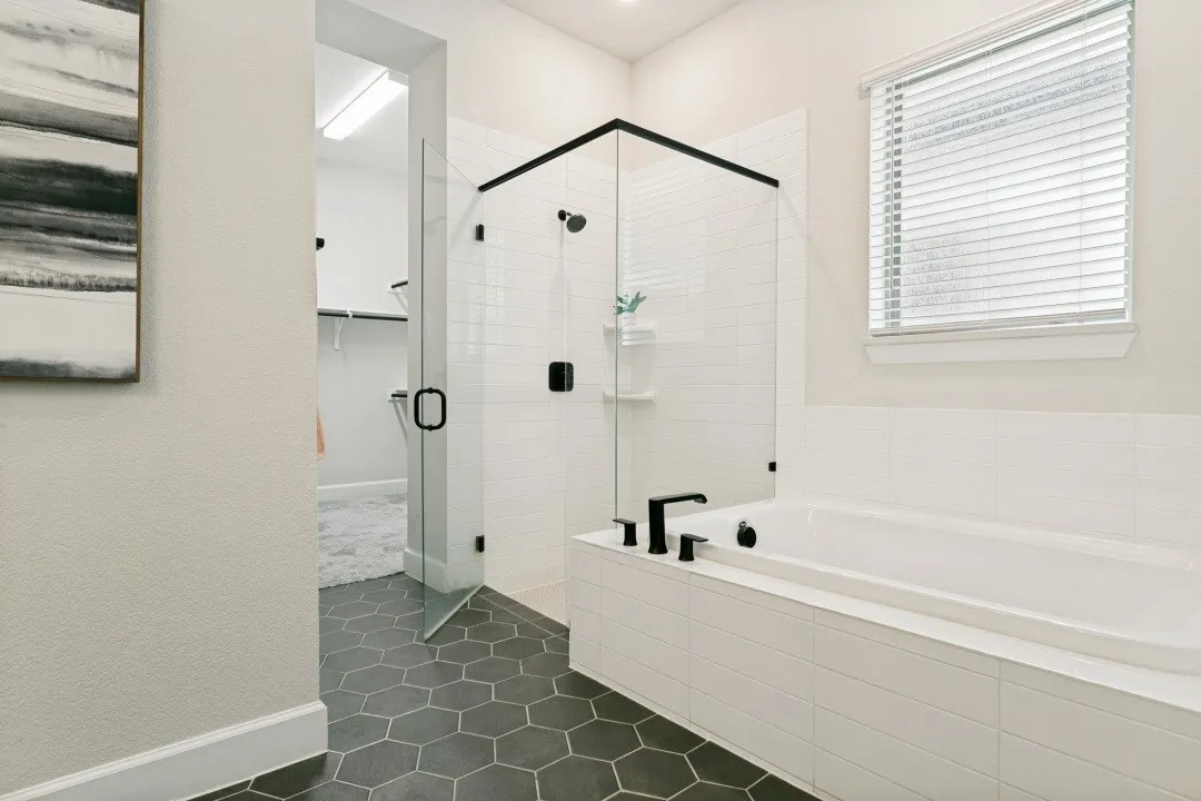 Bathroom featuring a soaking tub, glass-enclosed shower with matte black fixtures, and hexagonal floor tiling