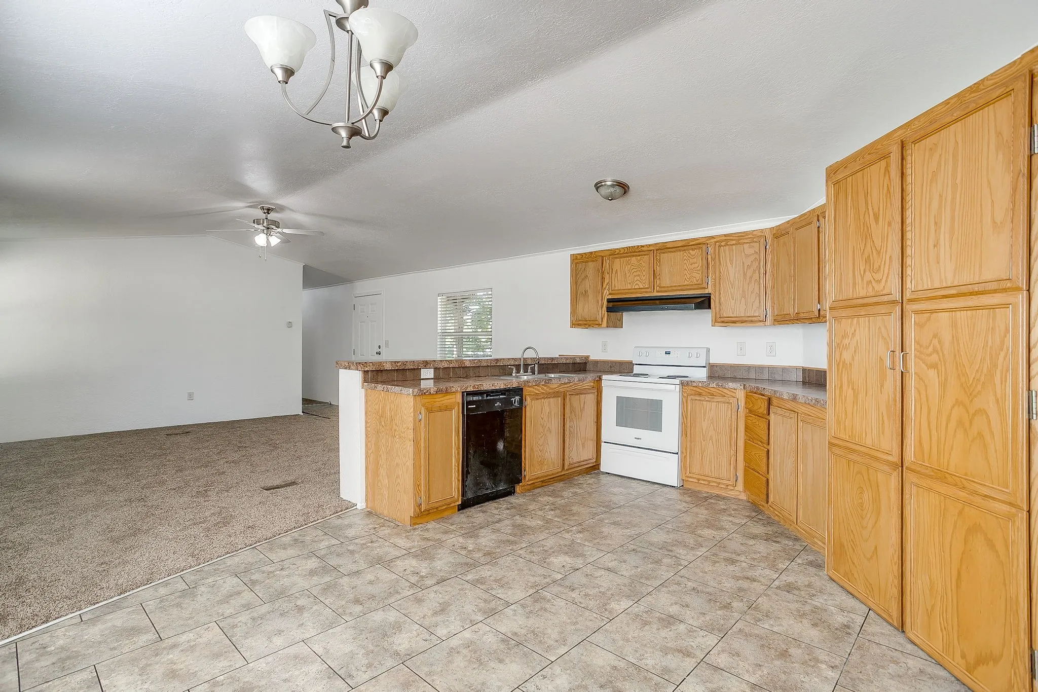 Kitchen featuring wood-finish cabinetry, tile flooring, white electric range, and black dishwasher
