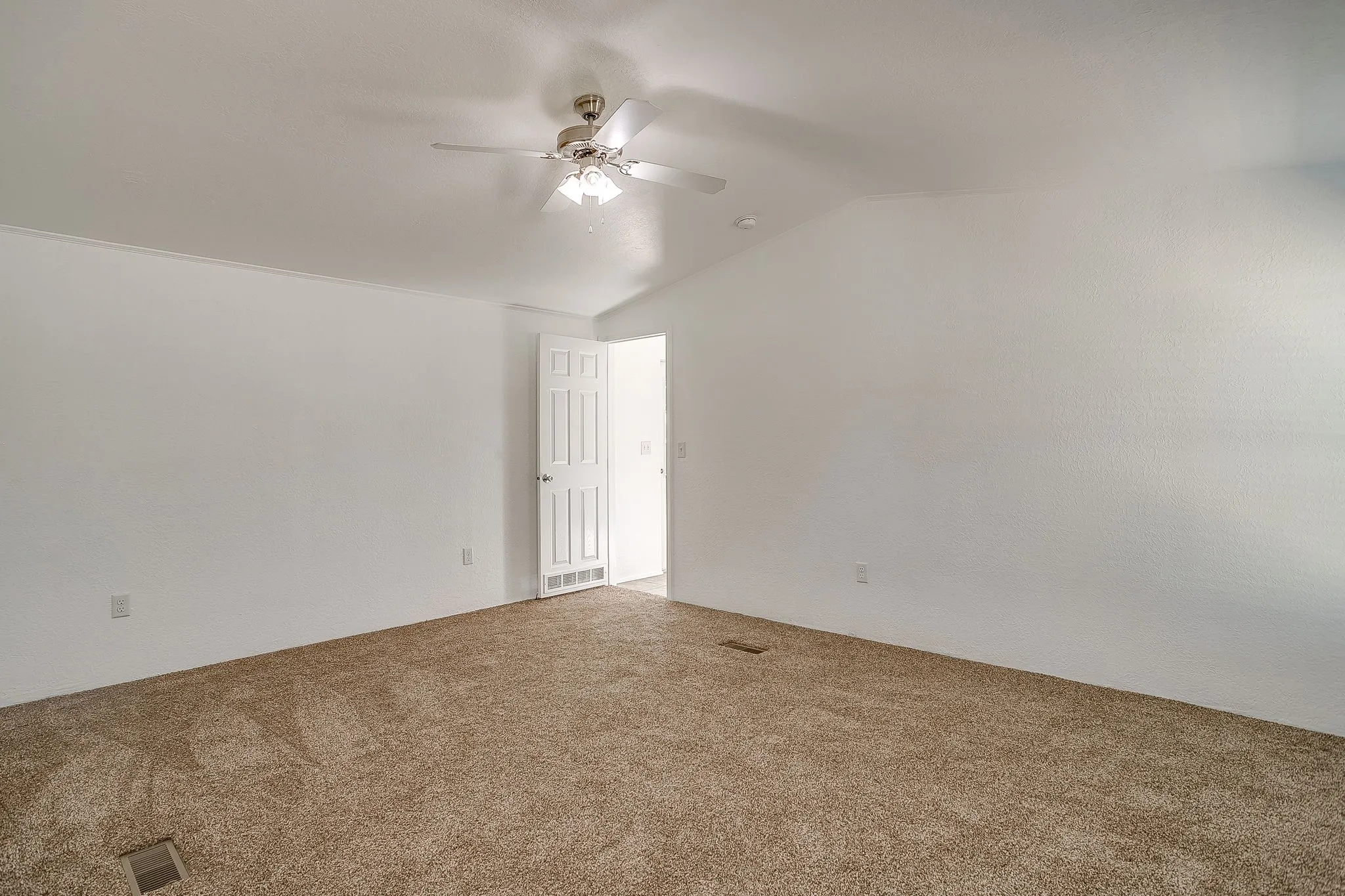 Spacious bedroom with neutral wall finishes, carpeted flooring, and ceiling fan with integrated lighting