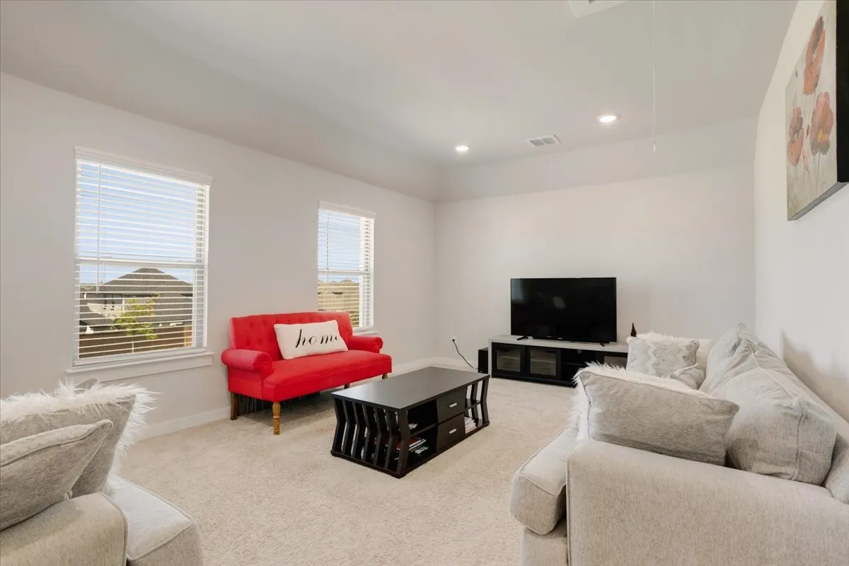 Recessed lighting, light-colored carpeting, two windows with blinds, and white wall finishes