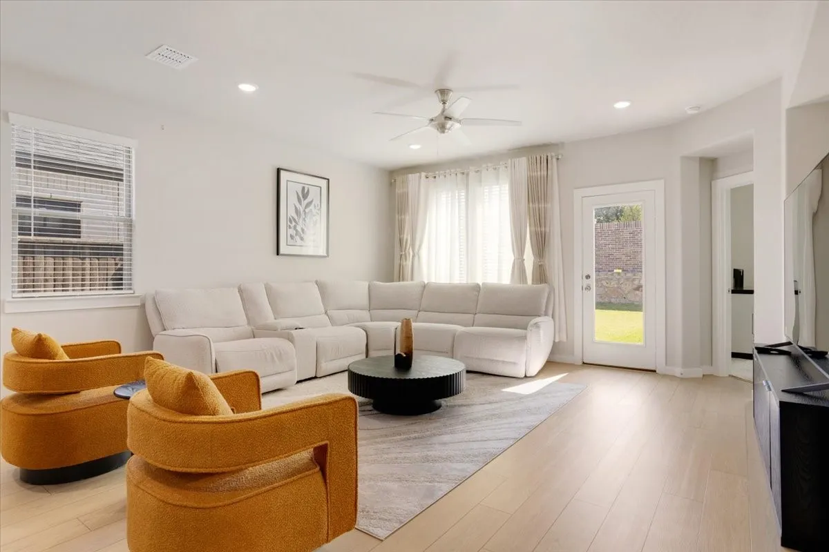 Recessed lighting, light wood-finish flooring, ceiling fan, white window blinds, and a glass-paneled door leading to an outdoor space