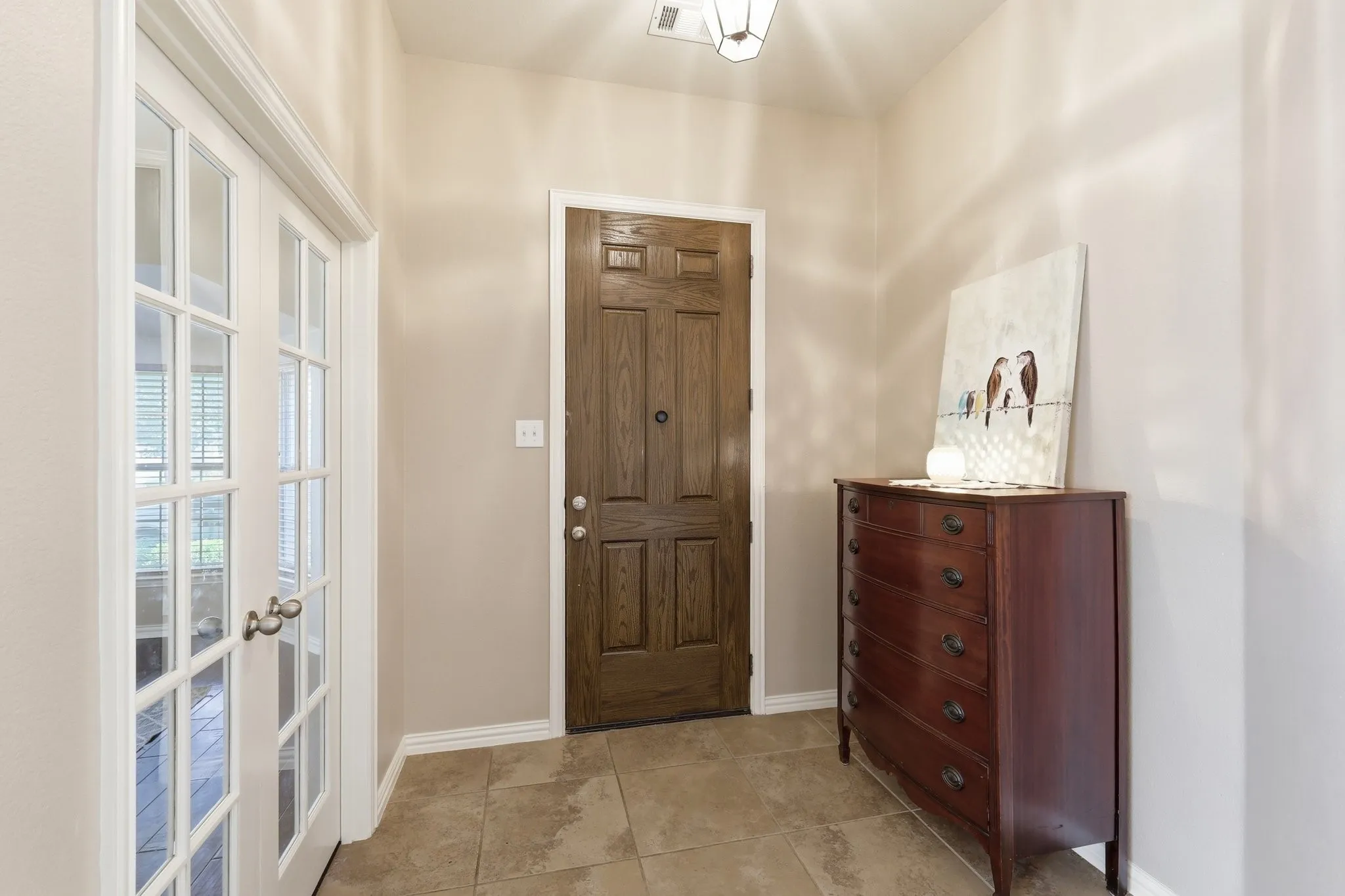 Foyer featuring light tile flooring, a paneled wood entry door, and French doors with white trim