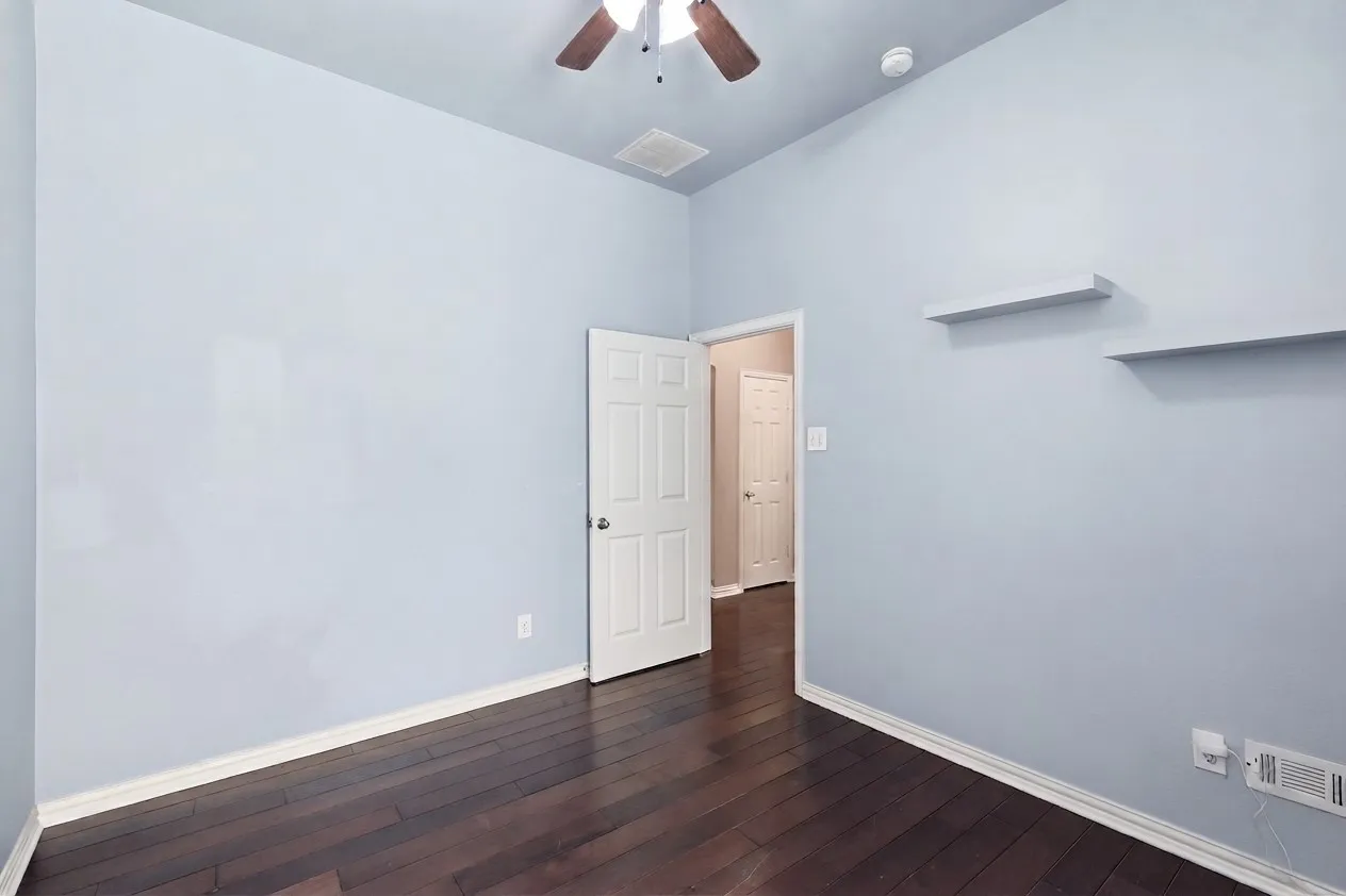 Downstair bedroom. Vaulted ceiling, wood-finish flooring, ceiling fan, window with blinds, and neutral wall paint