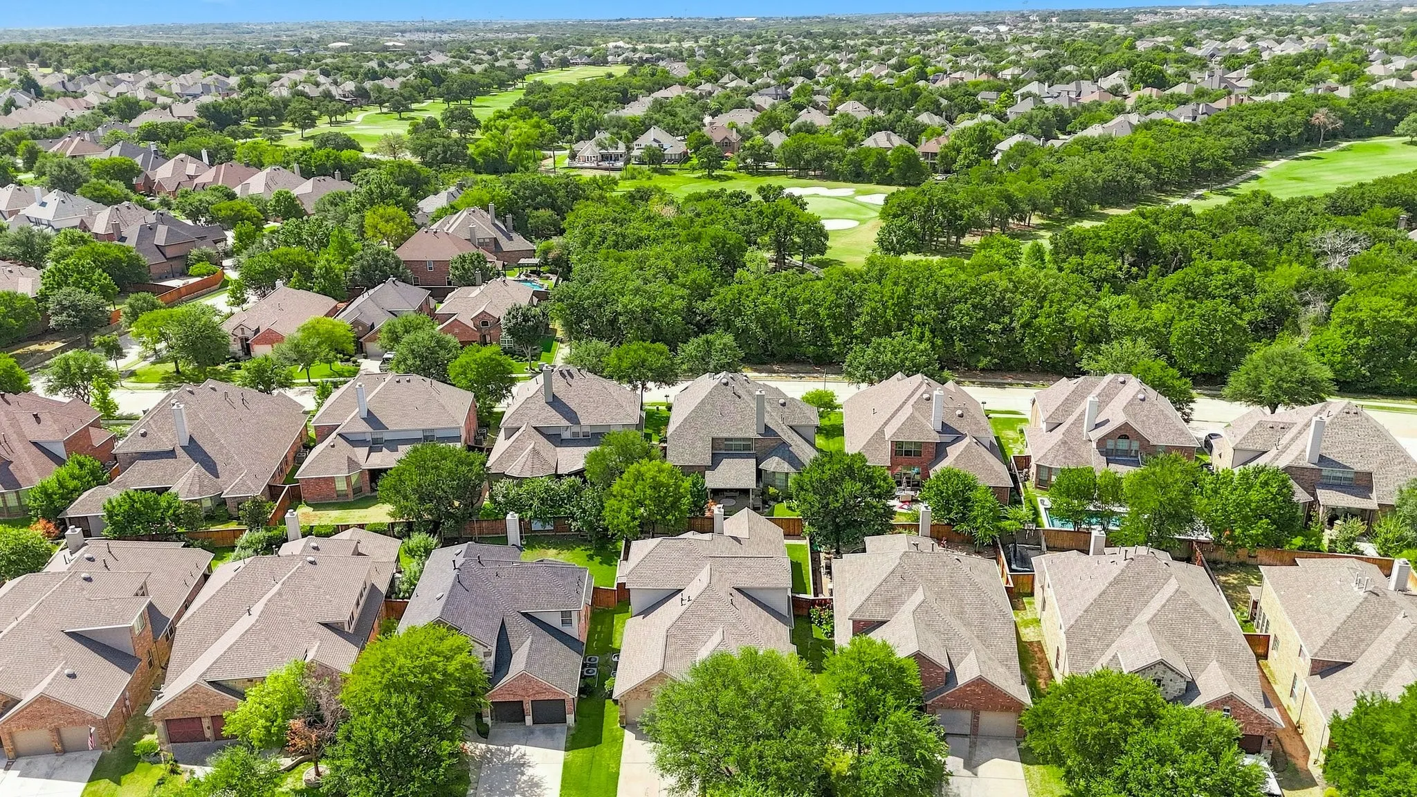 Residential properties with mature trees, shingle roofs, and brick or siding exteriors