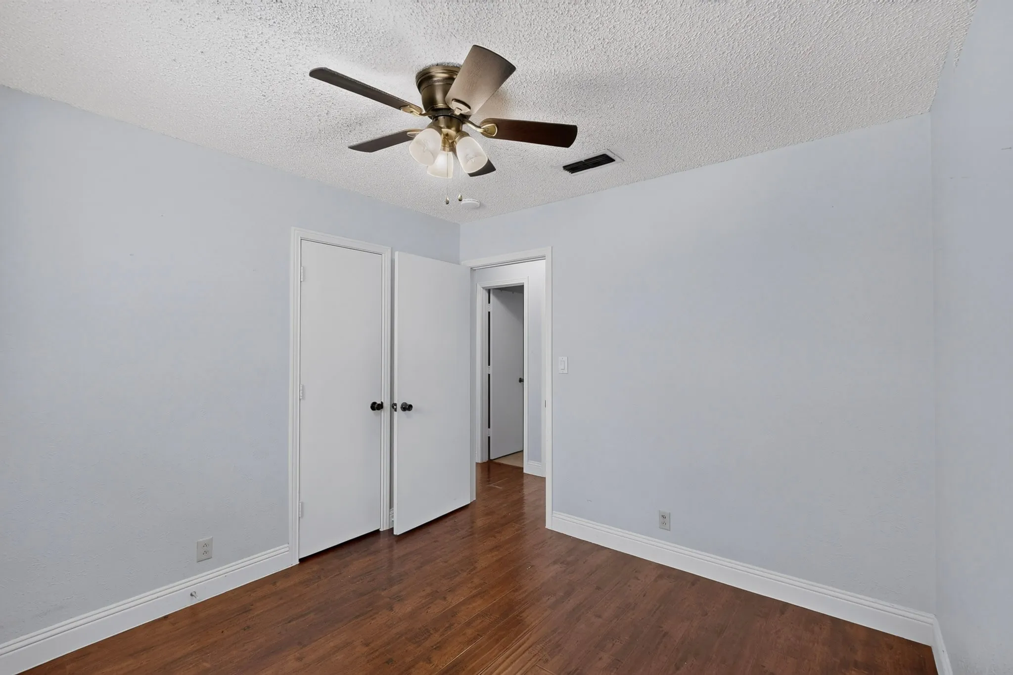 Wood-finish flooring, white baseboards, and ceiling fan with integrated lighting