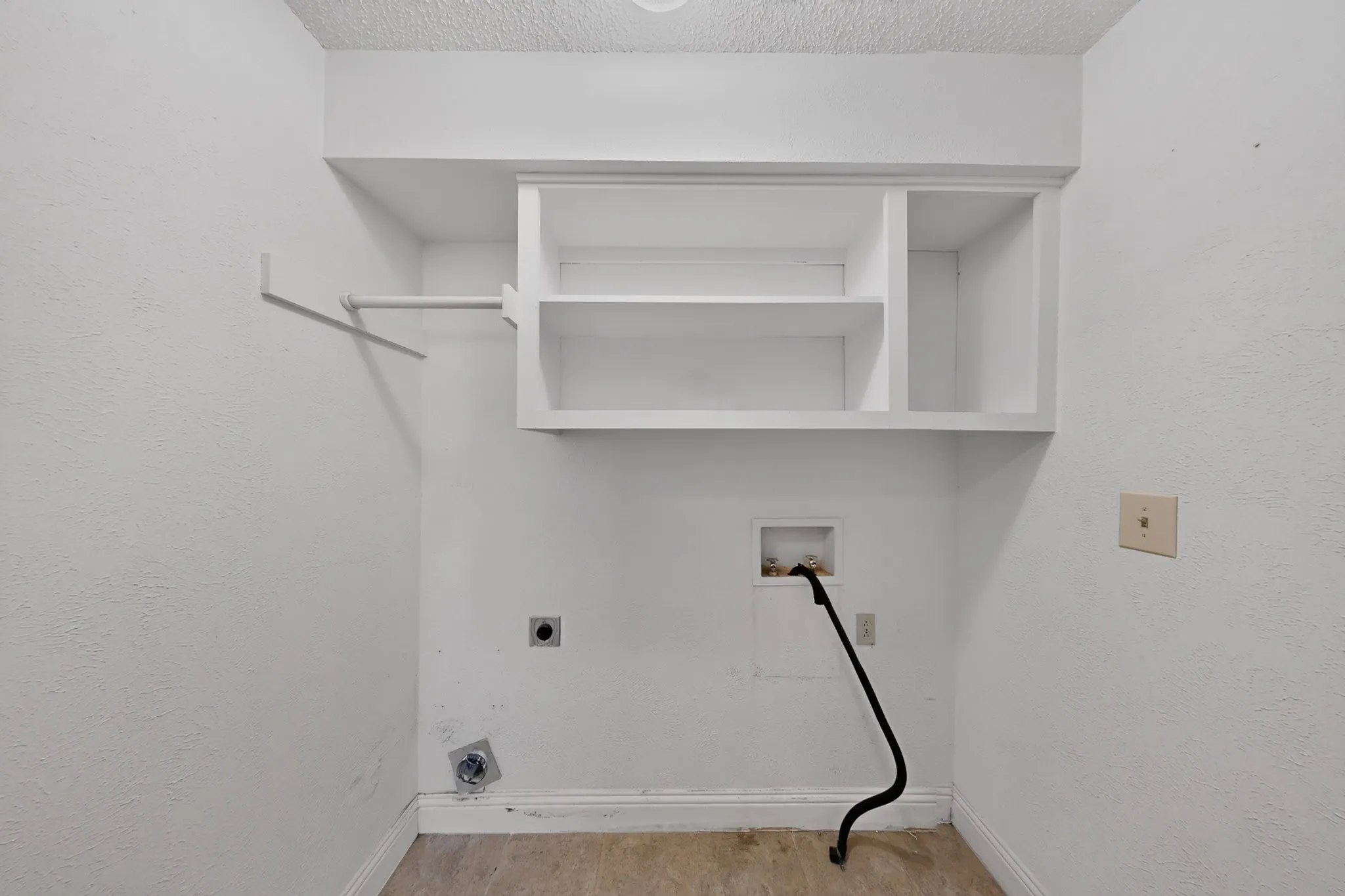 Built-in shelving, hanging rod, textured walls, and utility hookups,closet off Hallway
