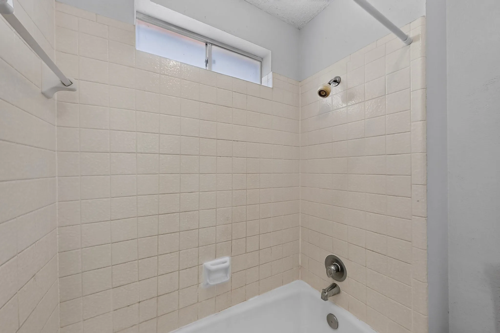 White tiled shower surround with an integrated bathtub