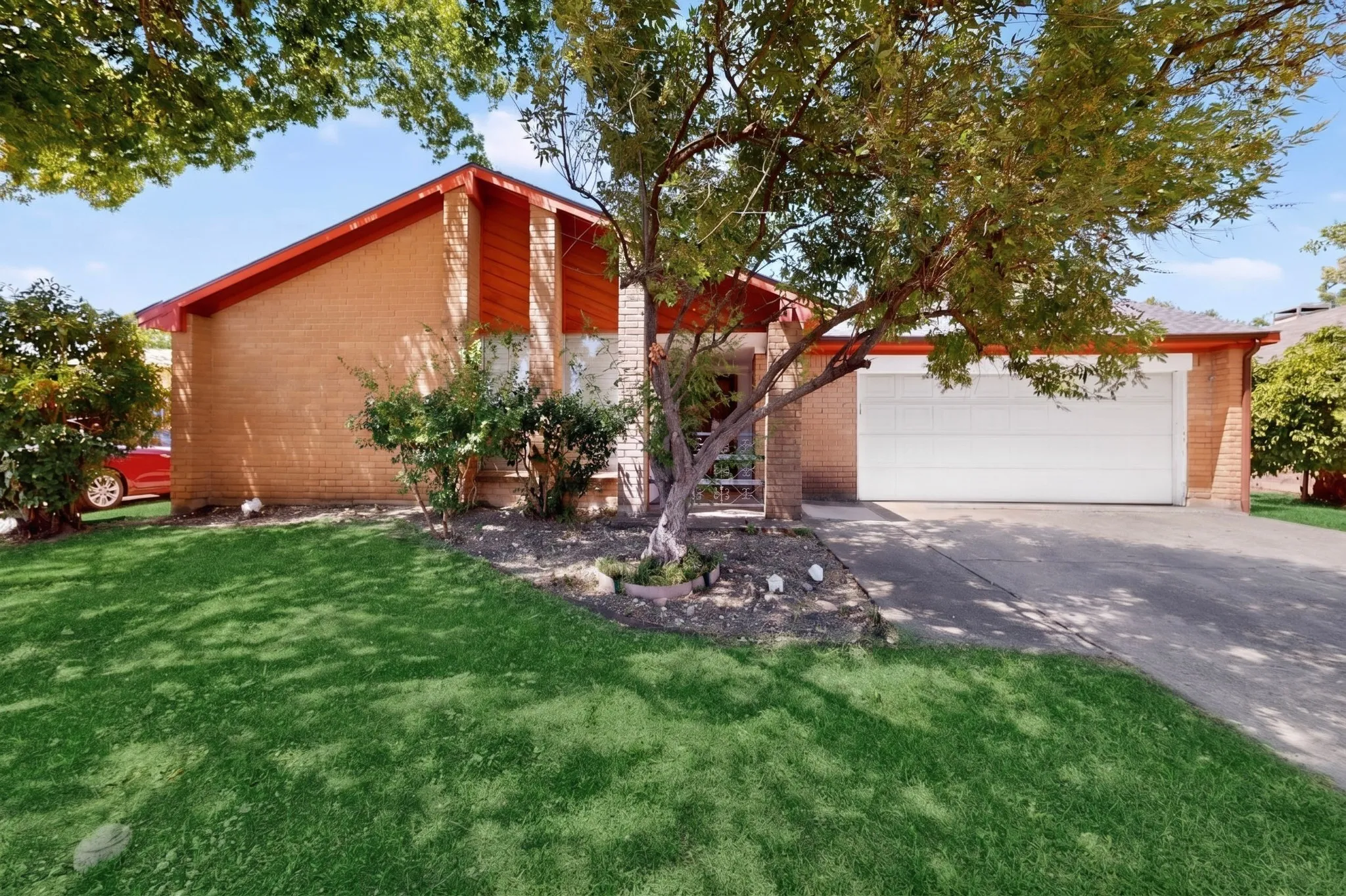 AI Brick exterior with an attached two-car garage, concrete driveway, and front lawn