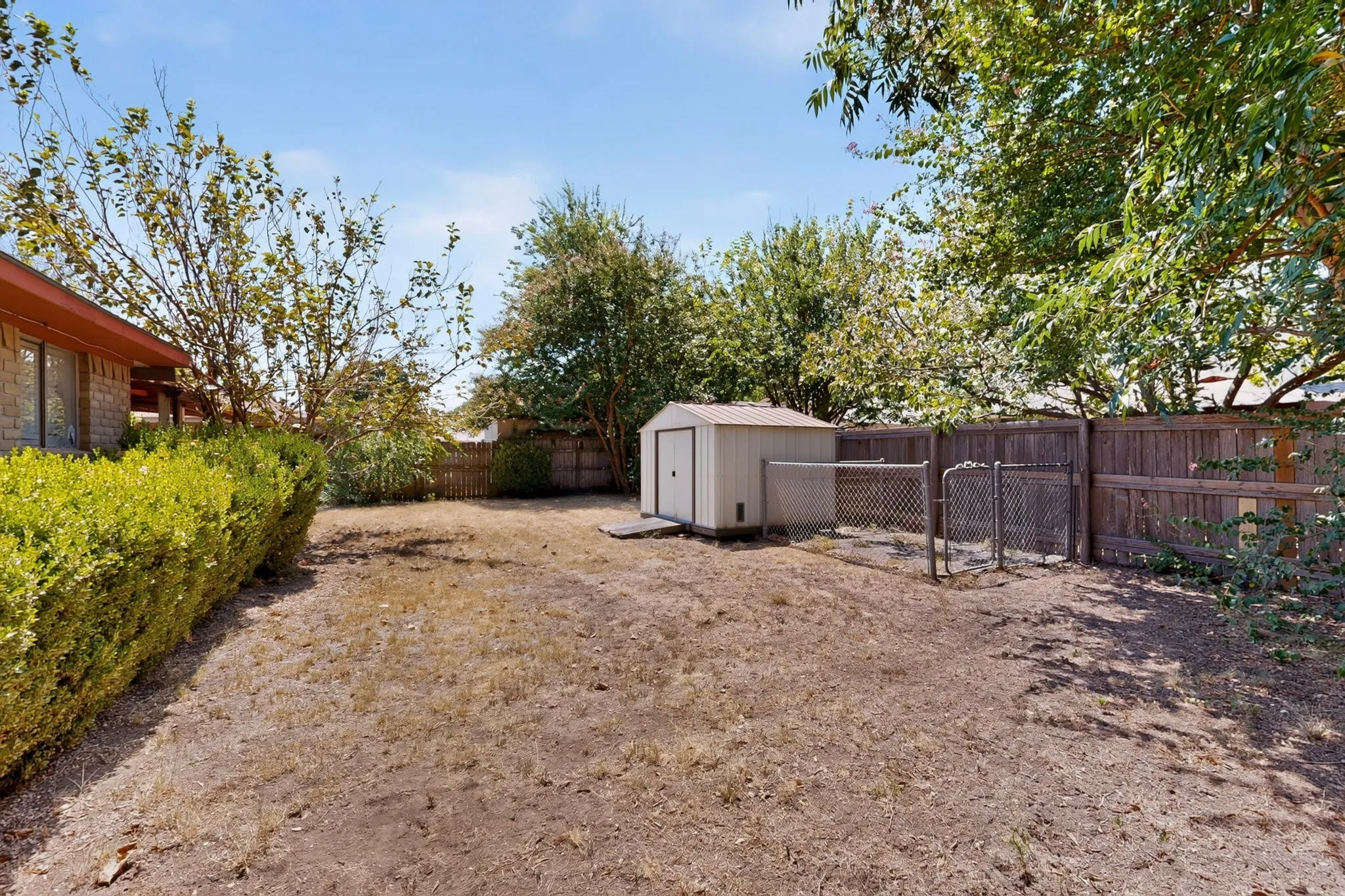 Backyard featuring a shed, chain-link fencing, and a wood privacy fence
