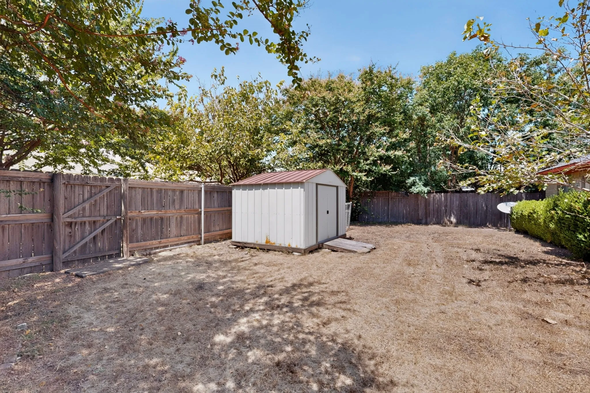 Enclosed backyard with wood privacy fencing, a storage shed, and mature perimeter trees