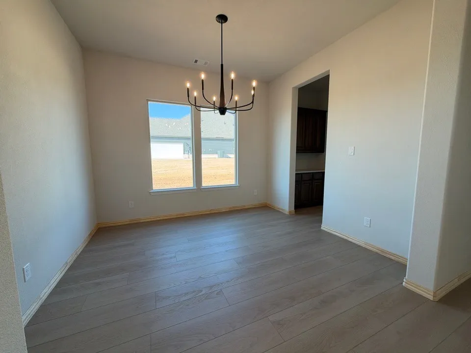 Wood-finish flooring throughout, modern black chandelier, white walls, and bright windows