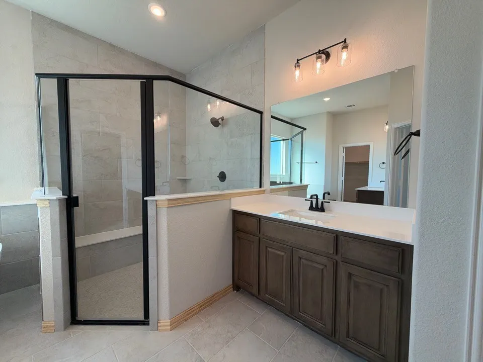 Walk-in shower with black-framed glass enclosure, tiled walls, and a built-in shelf
