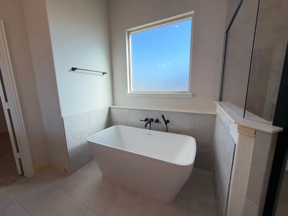 Freestanding soaking tub with matte black wall-mounted fixtures