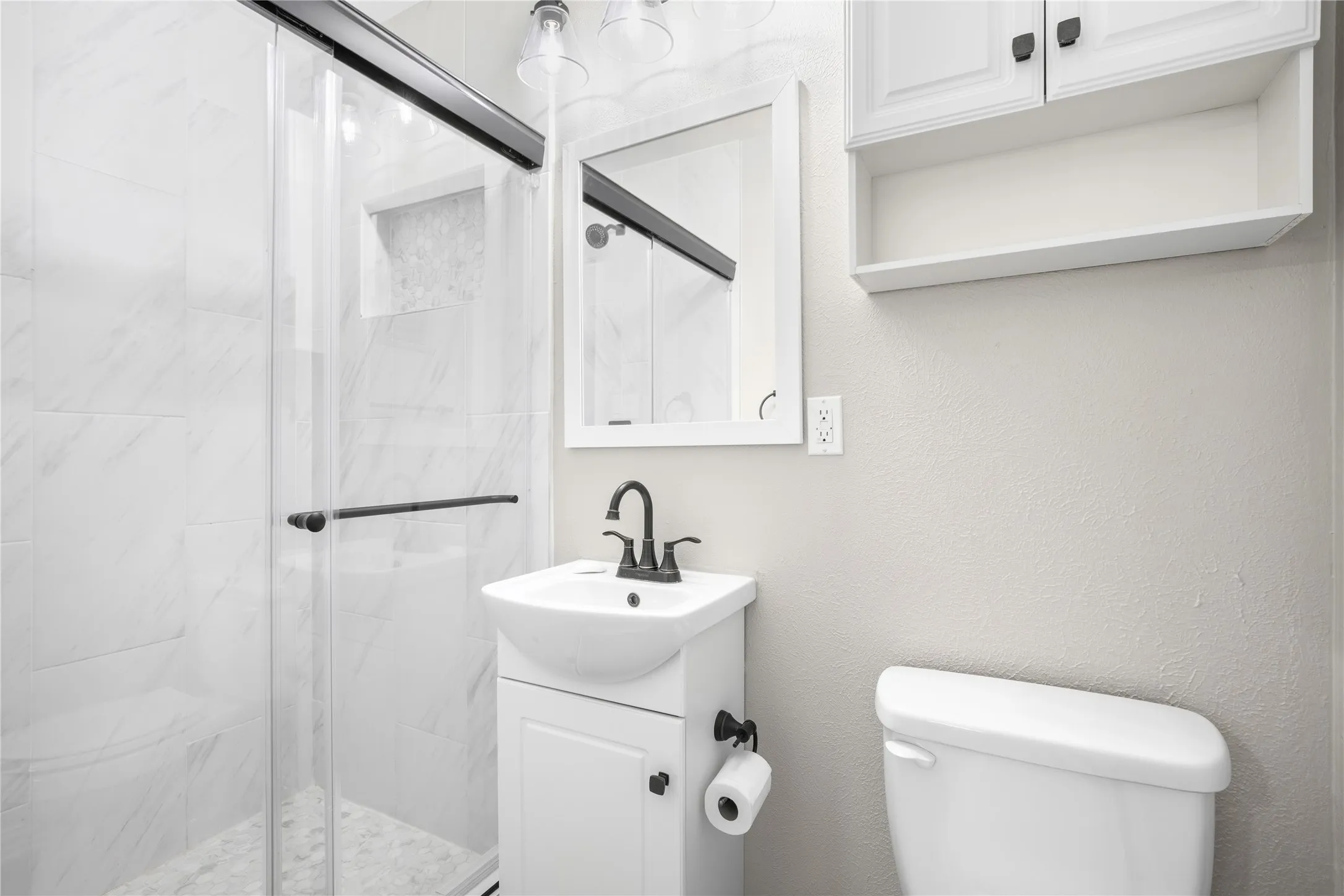 Glass-enclosed shower with tile surround and integrated niche