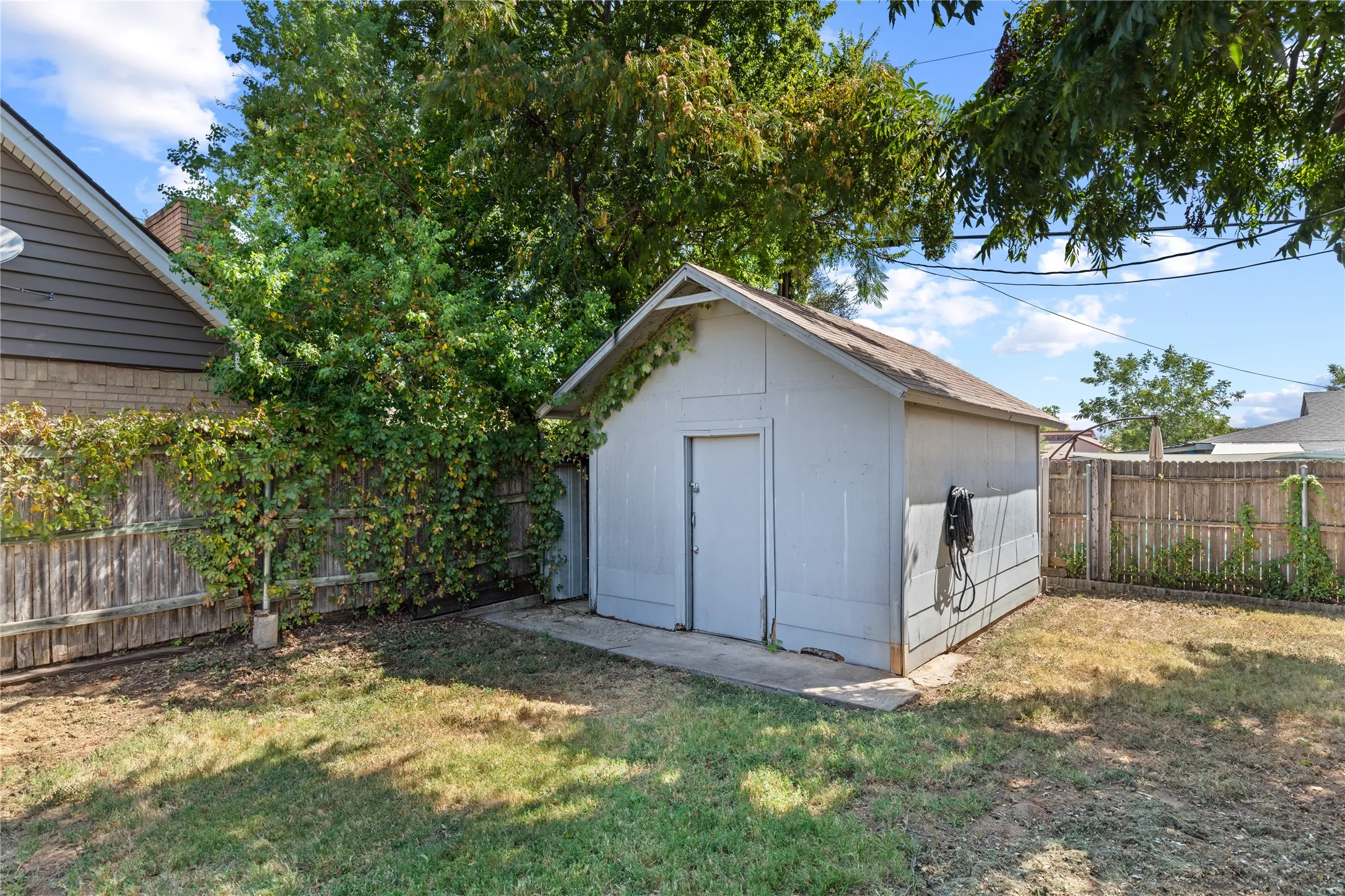Detached utility shed with a gable roof, concrete pad, and wood-panel siding